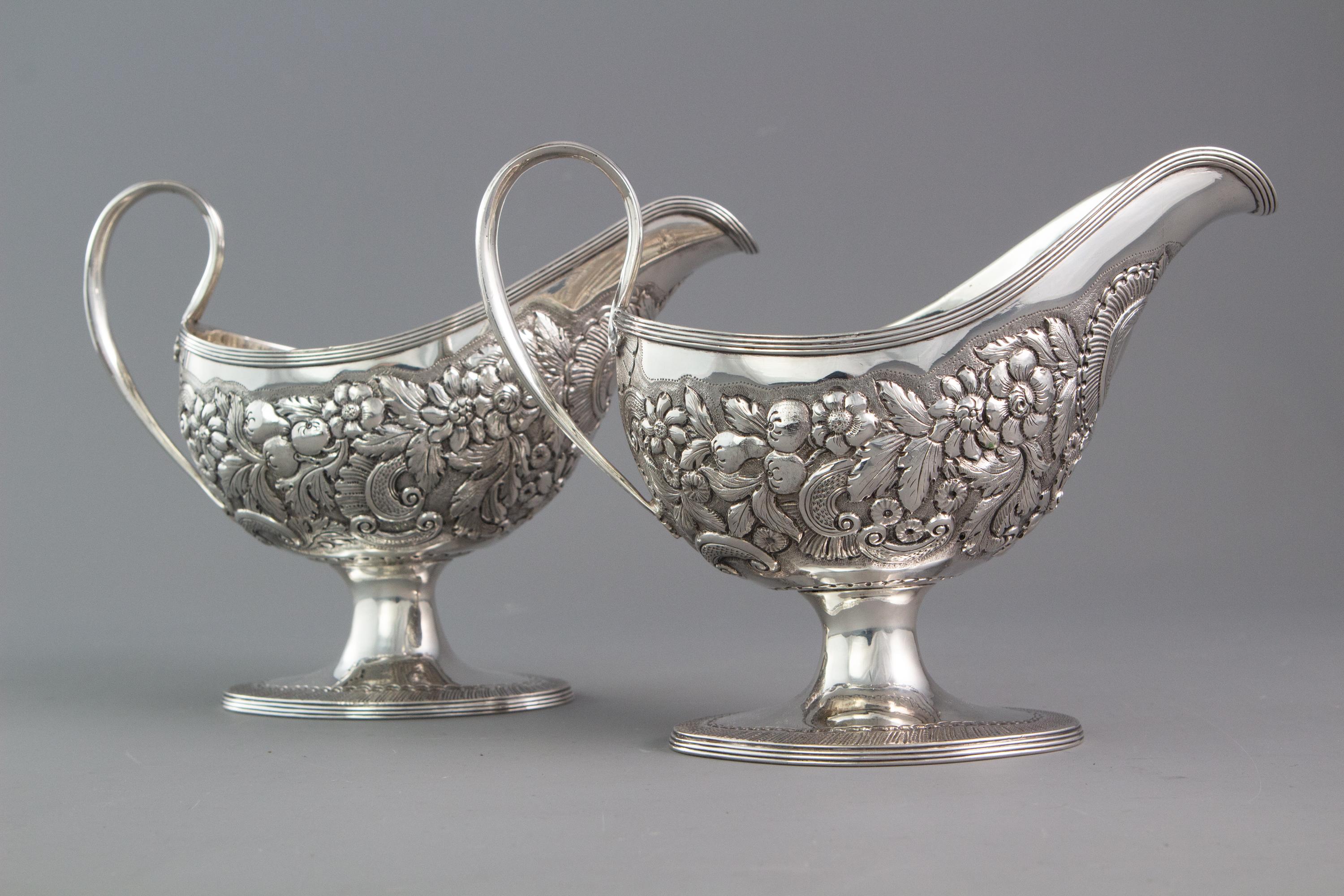This very attractive and rare pair of Irish sauce boats are of oval form. The shaped body with chased and embossed decoration with a gadrooned rim. The scrolling handle is decorated with an acanthus thumb piece and applied decoration. Both standing