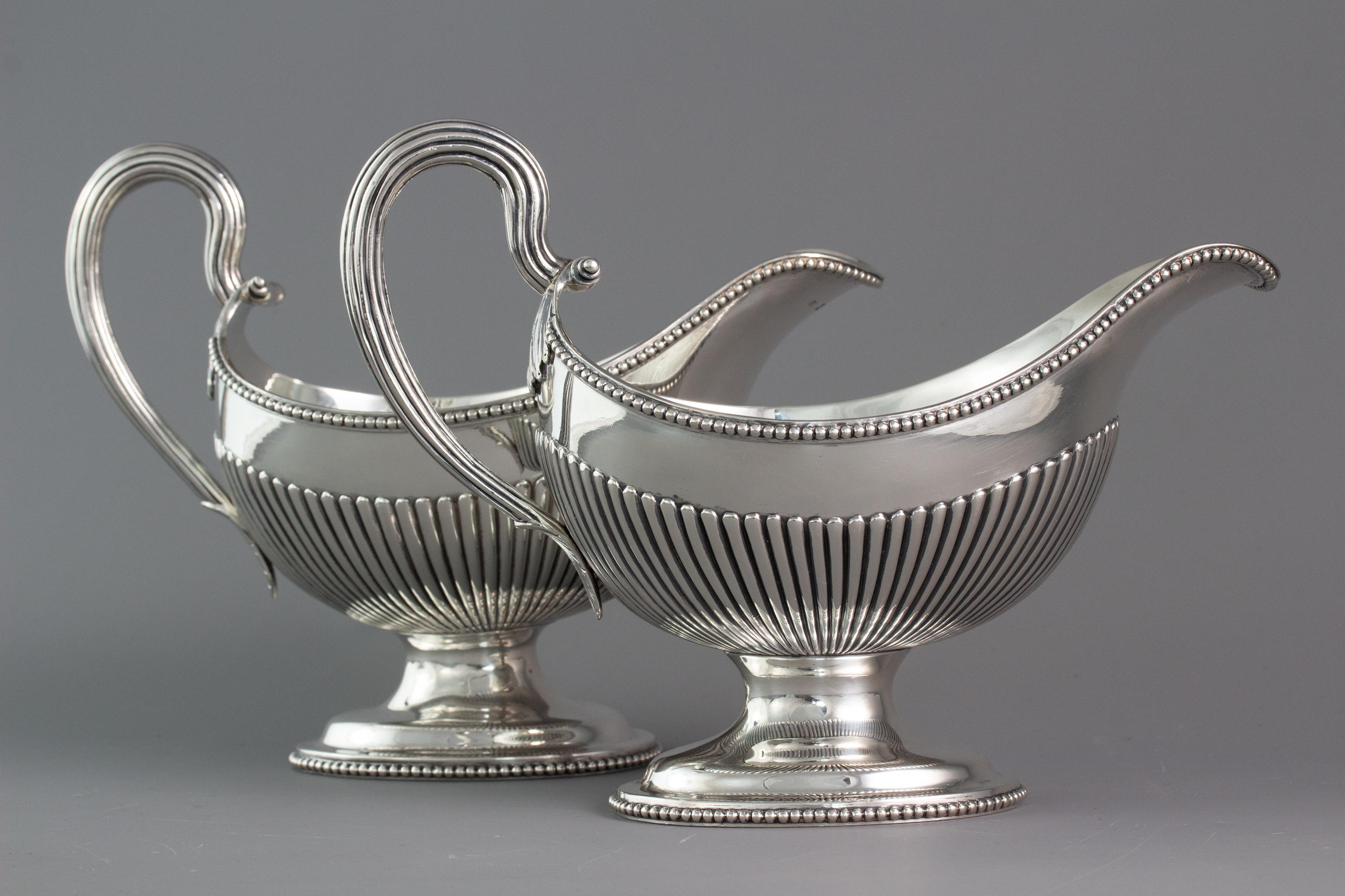 An unusual and very good pair of Georgian silver sauceboats each with a reeded scroll handle and beaded rim
above a half-reeded body, on an oval domed and beaded foot.

Marked to the body for London 1777 by Henry Brind.

Both boats are in