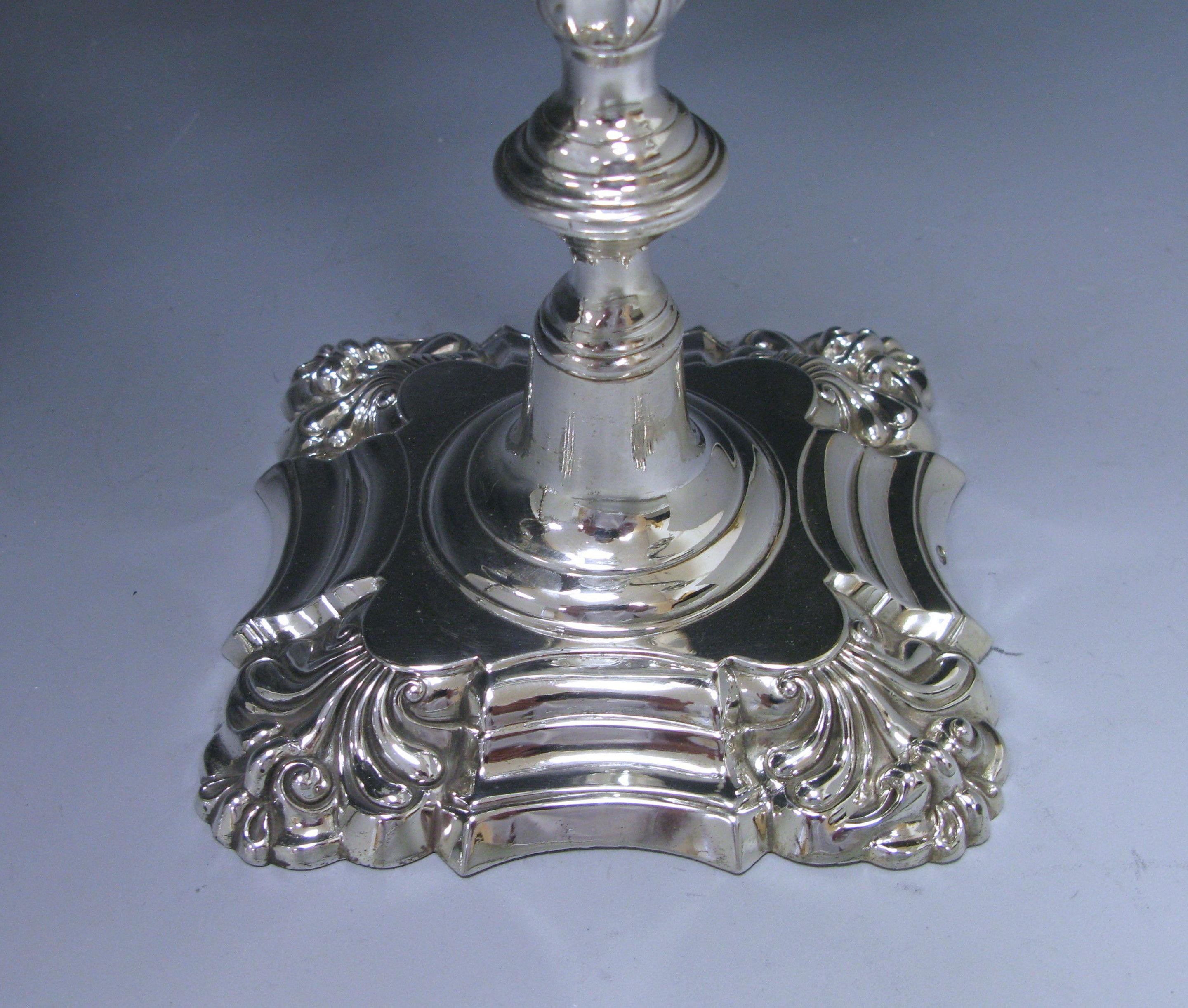 An outstanding pair cast antique silver three-light candelabra with knopped faceted columns to a four shell shaped base. The hallmarked push fit decorated arms are embellished with scrolling leaf decoration and each capital is surmounted with an