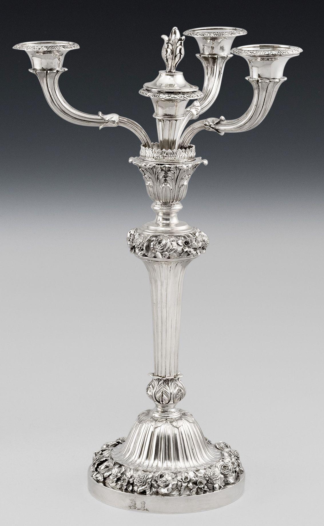 This important pair of George IV sterling silver candelabra are cast, have four lights and were made in London in 1825/26 by Benjamin Smith. The candelabra stand on a very unusual circular base decorated with a very crisp band of flower heads,