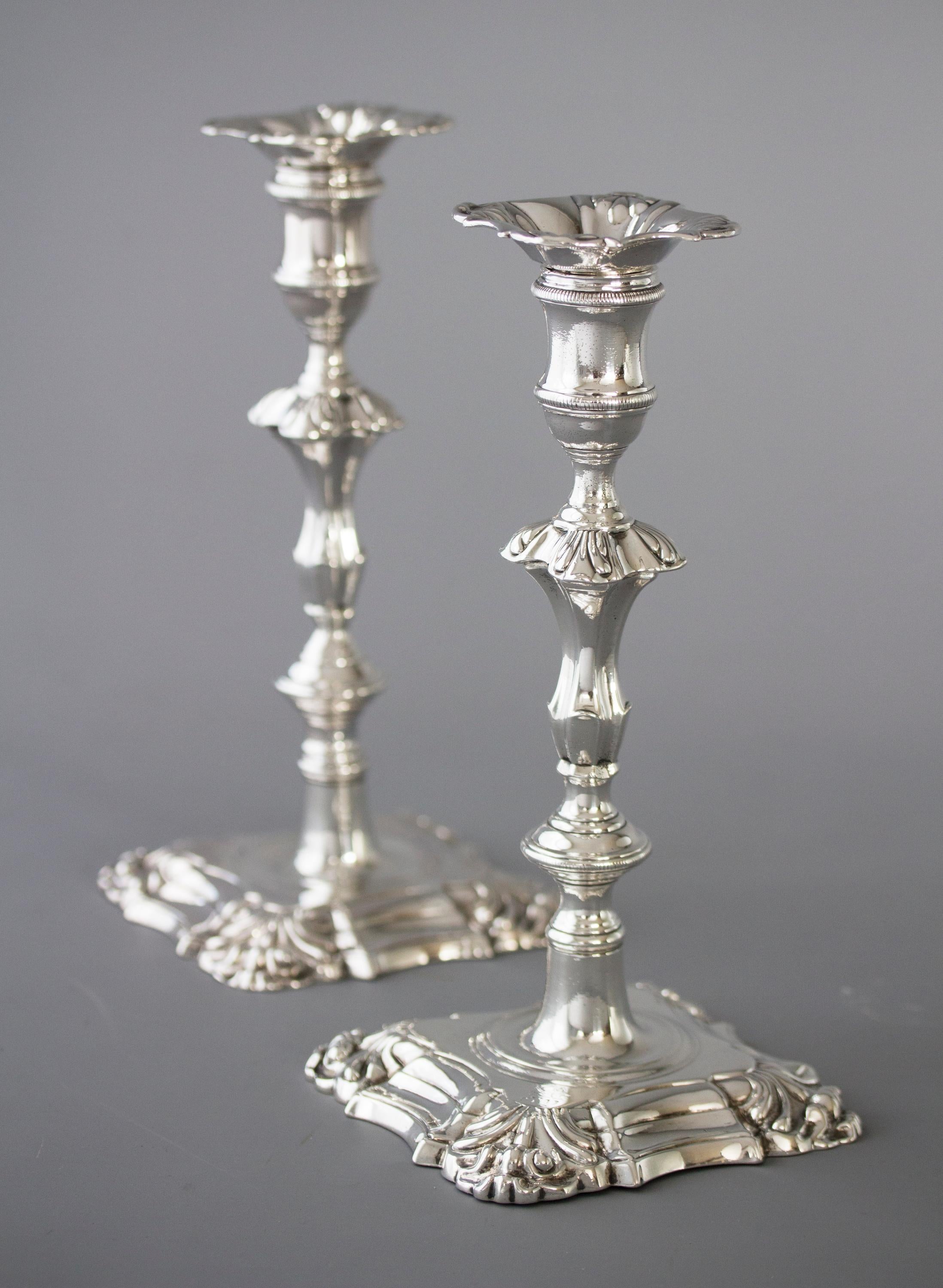 A very fine pair of George III cast silver table candlesticks with square bases shaped and stepped with shell form corners. The fluted columns rising above a rope twist knop to a square knop with conforming shell form corners. The capitals of cotton