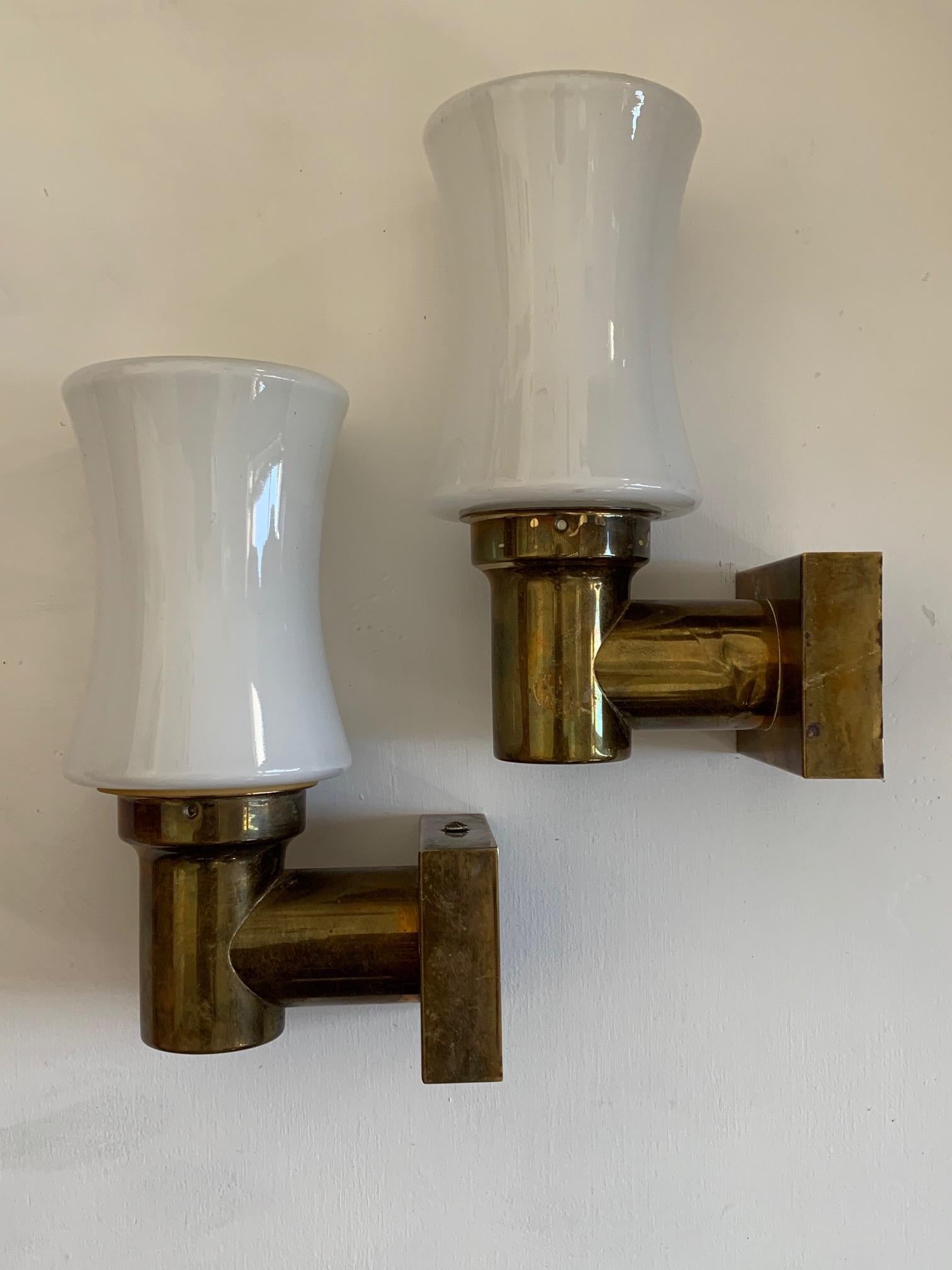 A pair of unusual sconces from Germany, circa 1950s. Brass and opaline glass, they can be hung up or down. Small scale, perfect as vanity/bathroom lights or anywhere in the room.