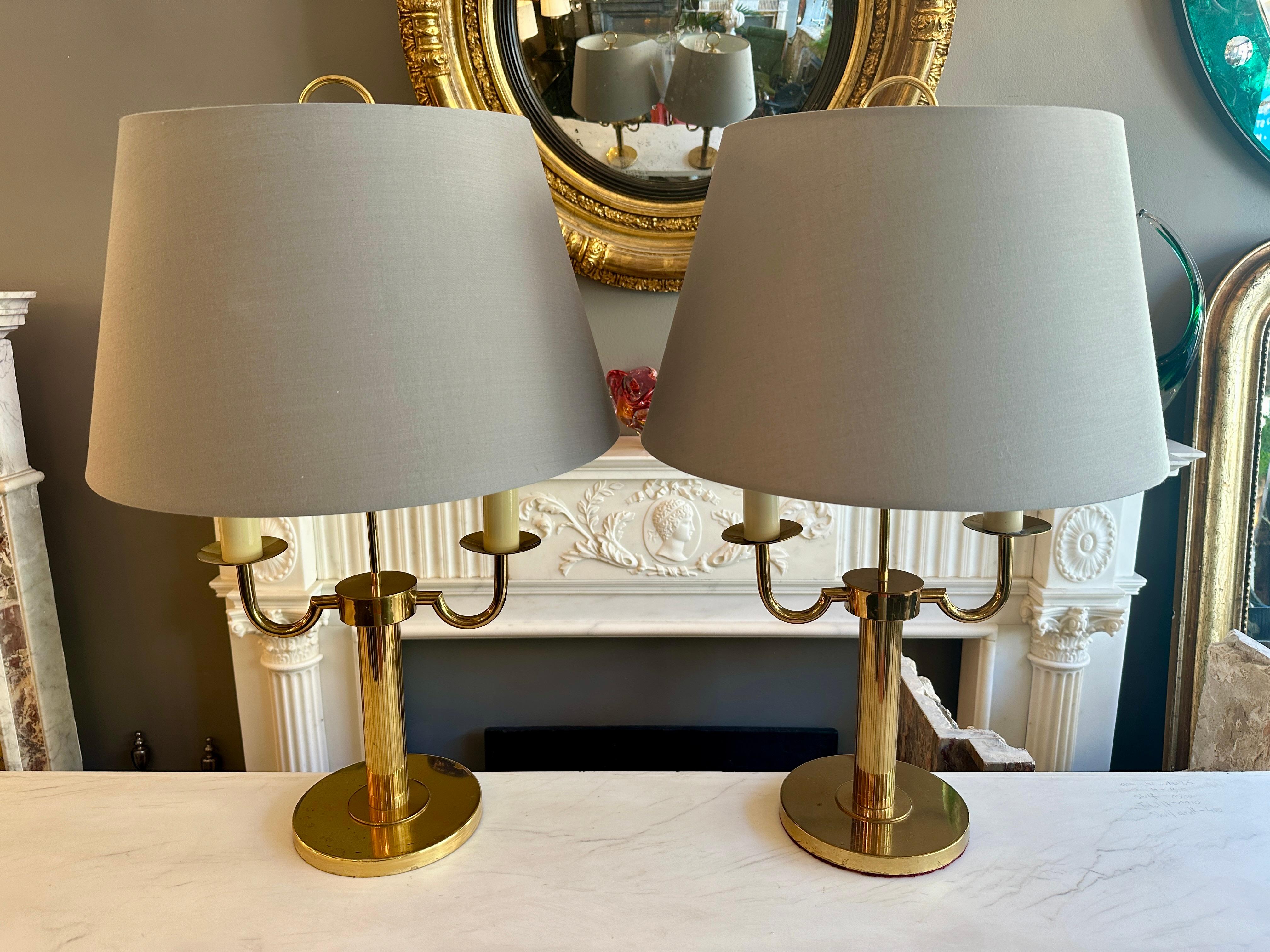 Paire de lampes de table de style Bouliotte en laiton doré du milieu du 20e siècle avec de nouveaux abat-jours en tissu gris. Le socle circulaire avec une tige cannelée supporte deux hauts bras de style bougie. Les sommets circulaires accentués