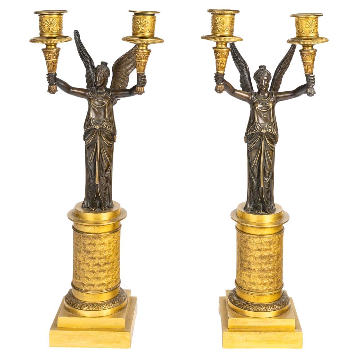 Paire de candélabres en bronze doré et patiné représentant des victoires ailés. en vente