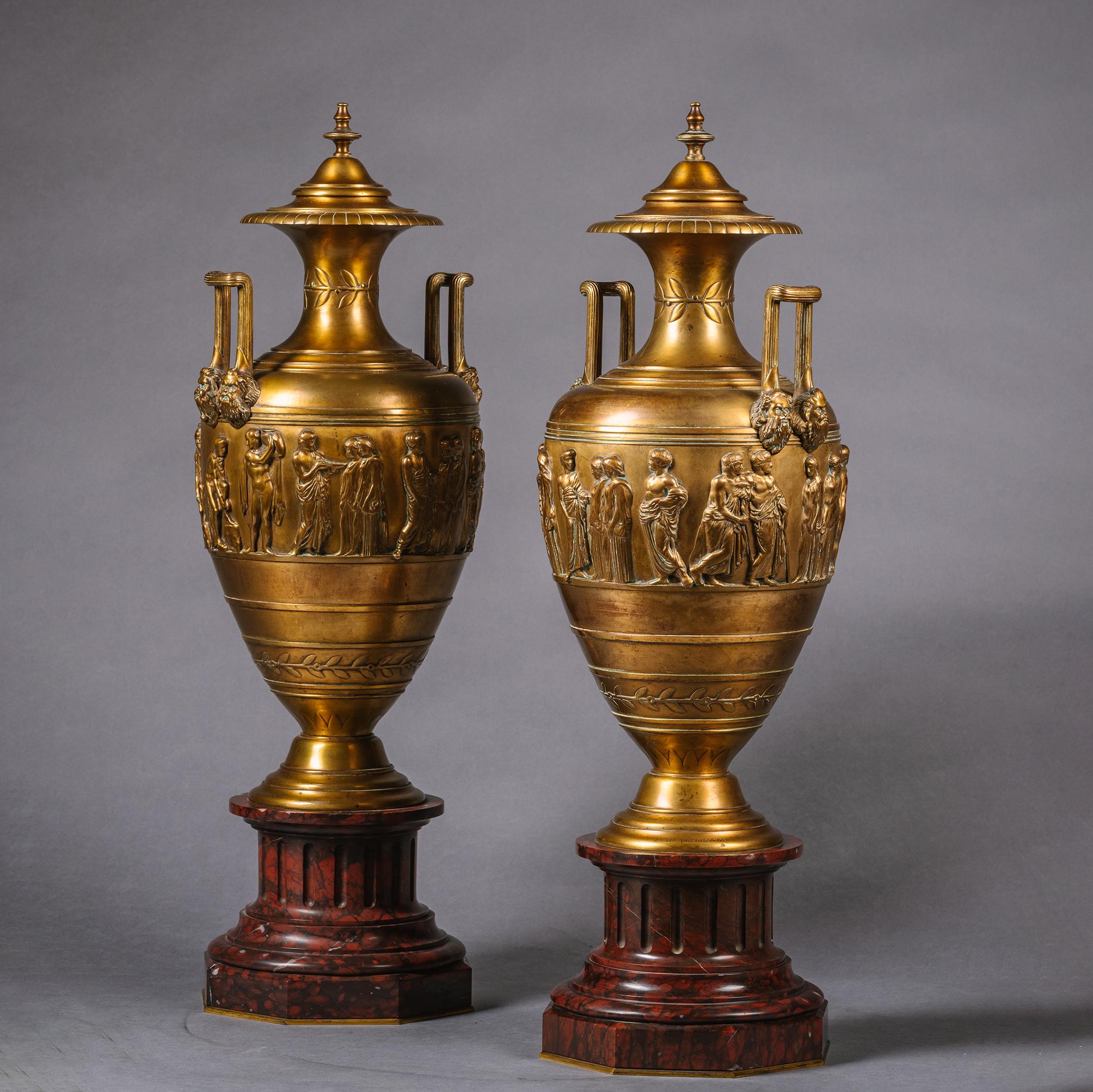 A Pair of Gilt-Bronze And Rouge Griotte Marble Vases and Covers. By Ferdinand Barbedienne, Paris. 

Designed in the Neo-Grec style these elegant vases stand atop Rouge Griotte marble plinths. Each vase has a fixed cover with finial above flared