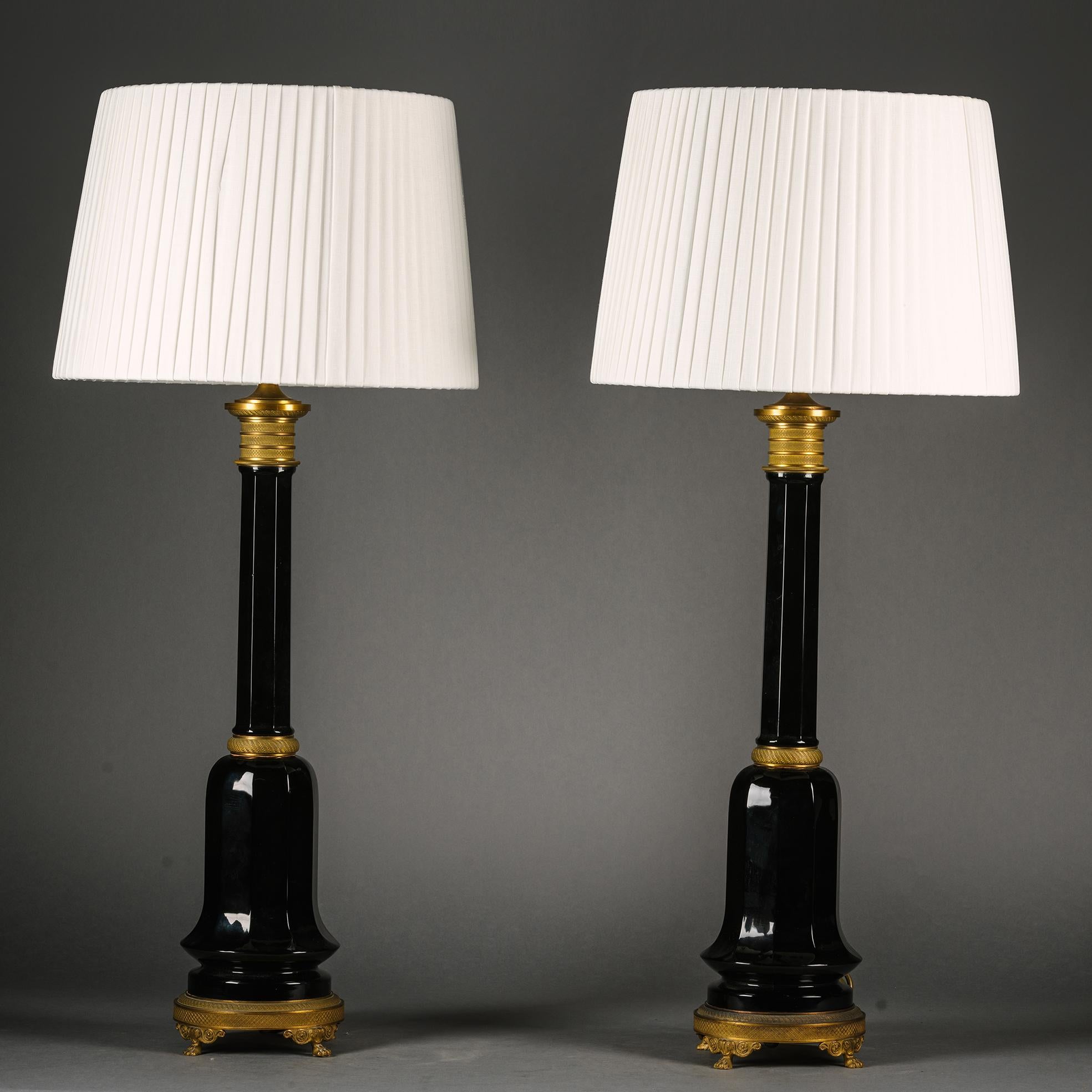 A Pair of Gilt-Bronze and Ruby Glass Table Lamps. 

Each with hexagonal stem and tulip-shaped Bohemian glass base. The metalwork finely turned with crosshatched patterns in gilt-bronze.

Probably France. Circa 1900.

Height: not including shades 71