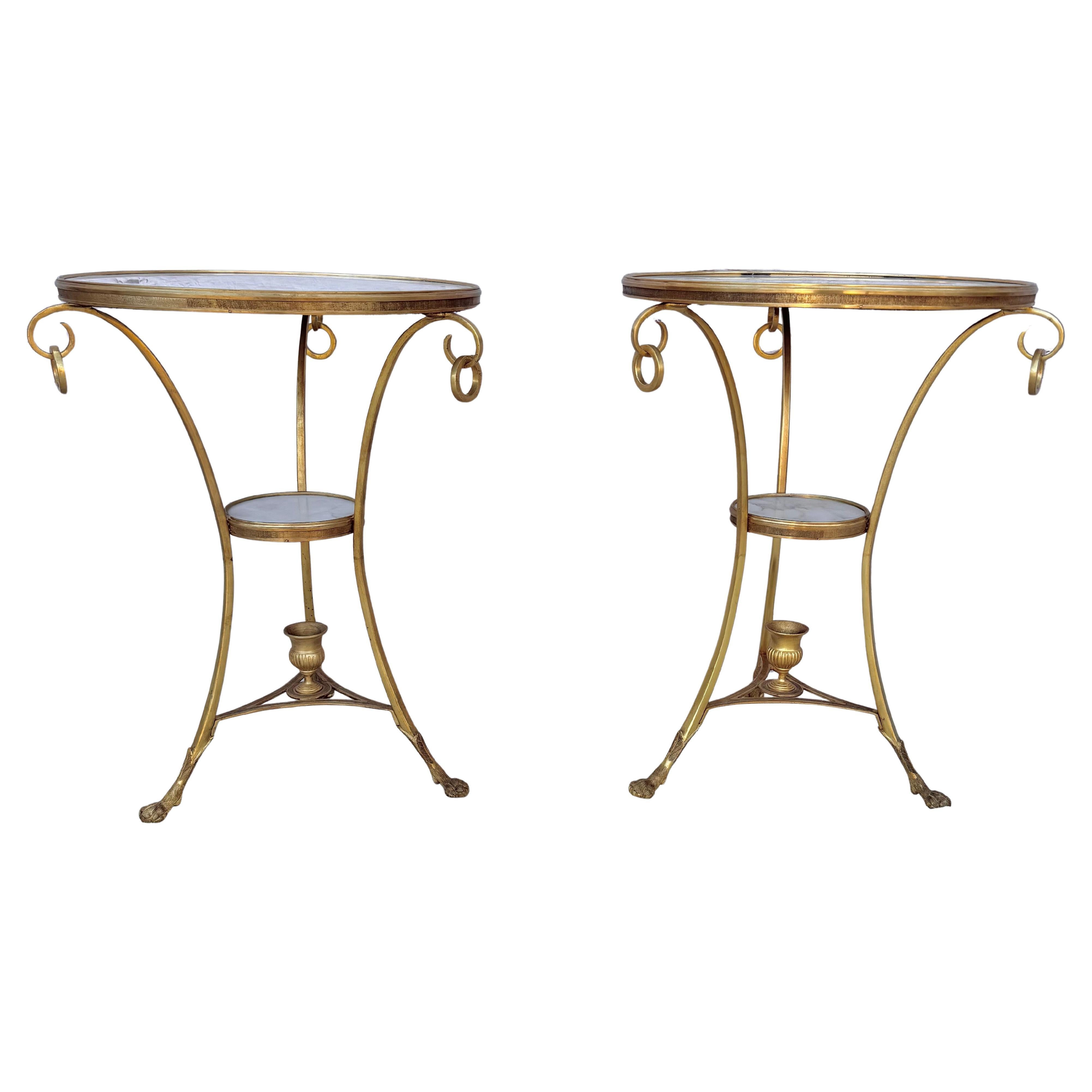 Paire de tables Guèridon en bronze doré et marbre blanc. L'ensemble comprend de petites tables rondes dont le plateau en marbre repose sur trois supports incurvés reliés par une tablette en marbre sur un triangle centré par une urne et se terminant