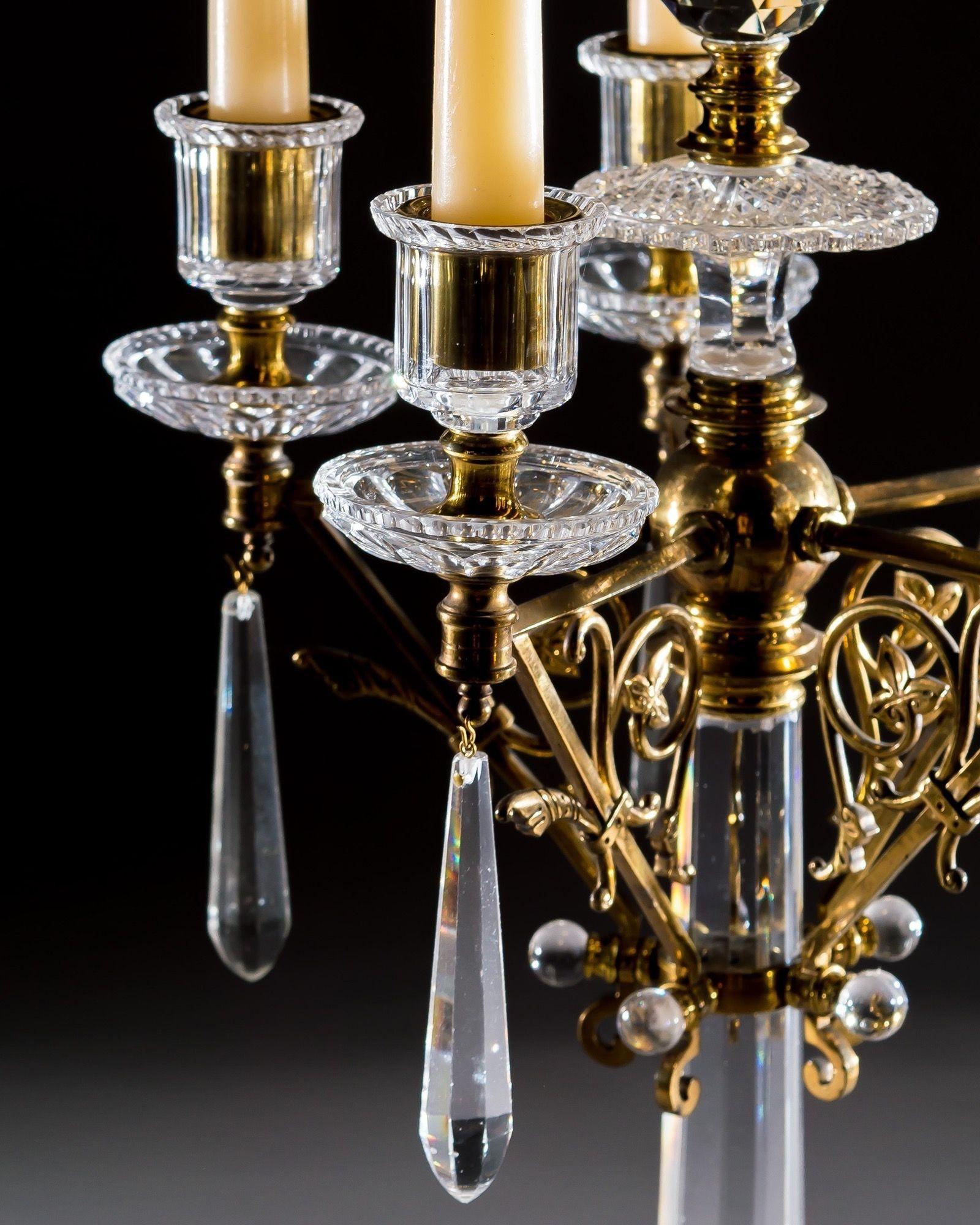 The fabulous pair of gilt bronze cut glass Victorian candelabra are of arts and crafts form. The flat diamond cut bases with applied gilt bands and tapering columns, supporting five decorative branches fitted with drip pans, candle nozzles and hung