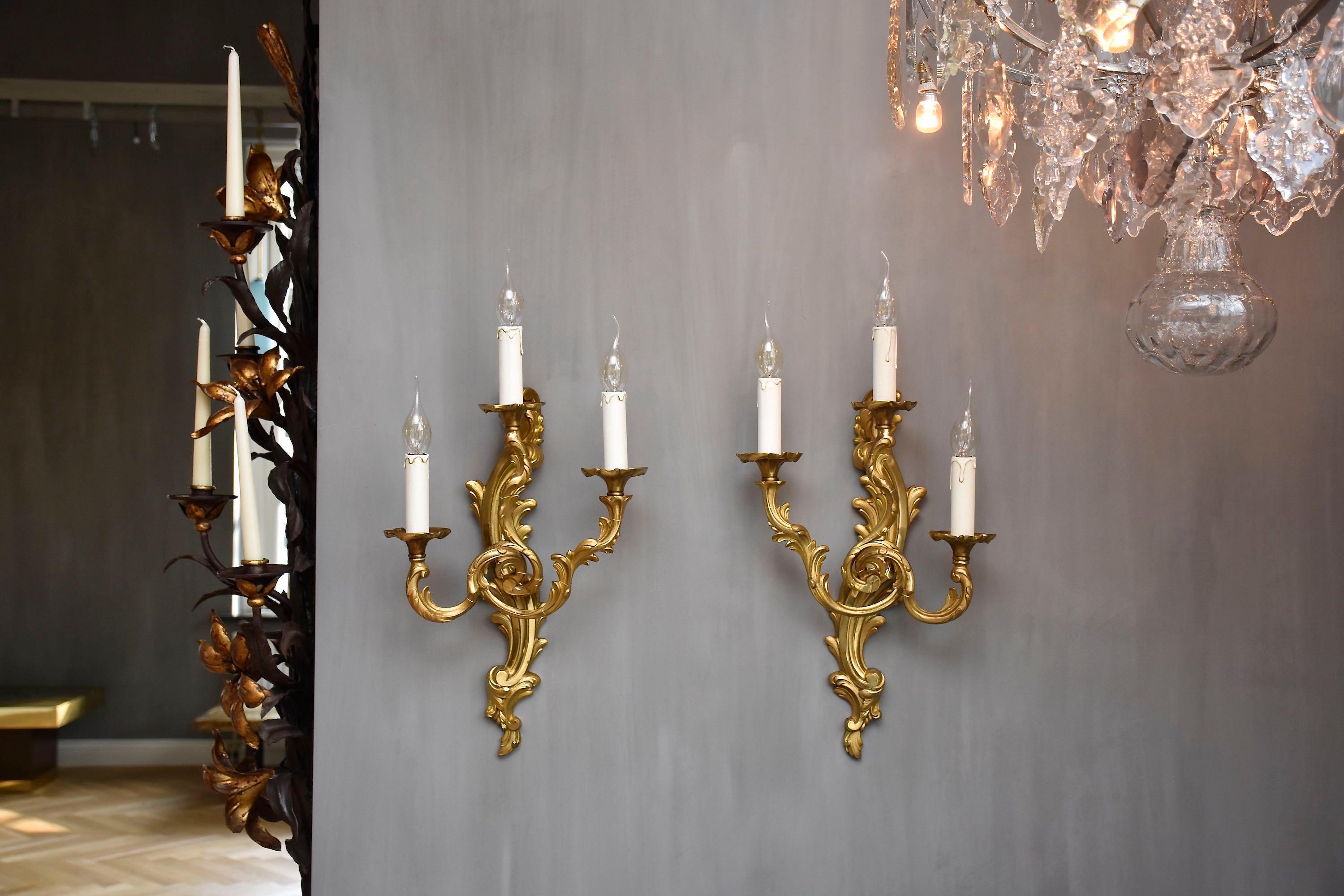 Elegante pareja de dos apliques franceses de bronce dorado, cada uno con 3 luces. 
Con decoración rocaille.
Estilo -Luis XV
Lugar de origen- Francia
Periodo- s. XX

La altura total, incluidos los accesorios de iluminación, es de unos 57 cm.
La
