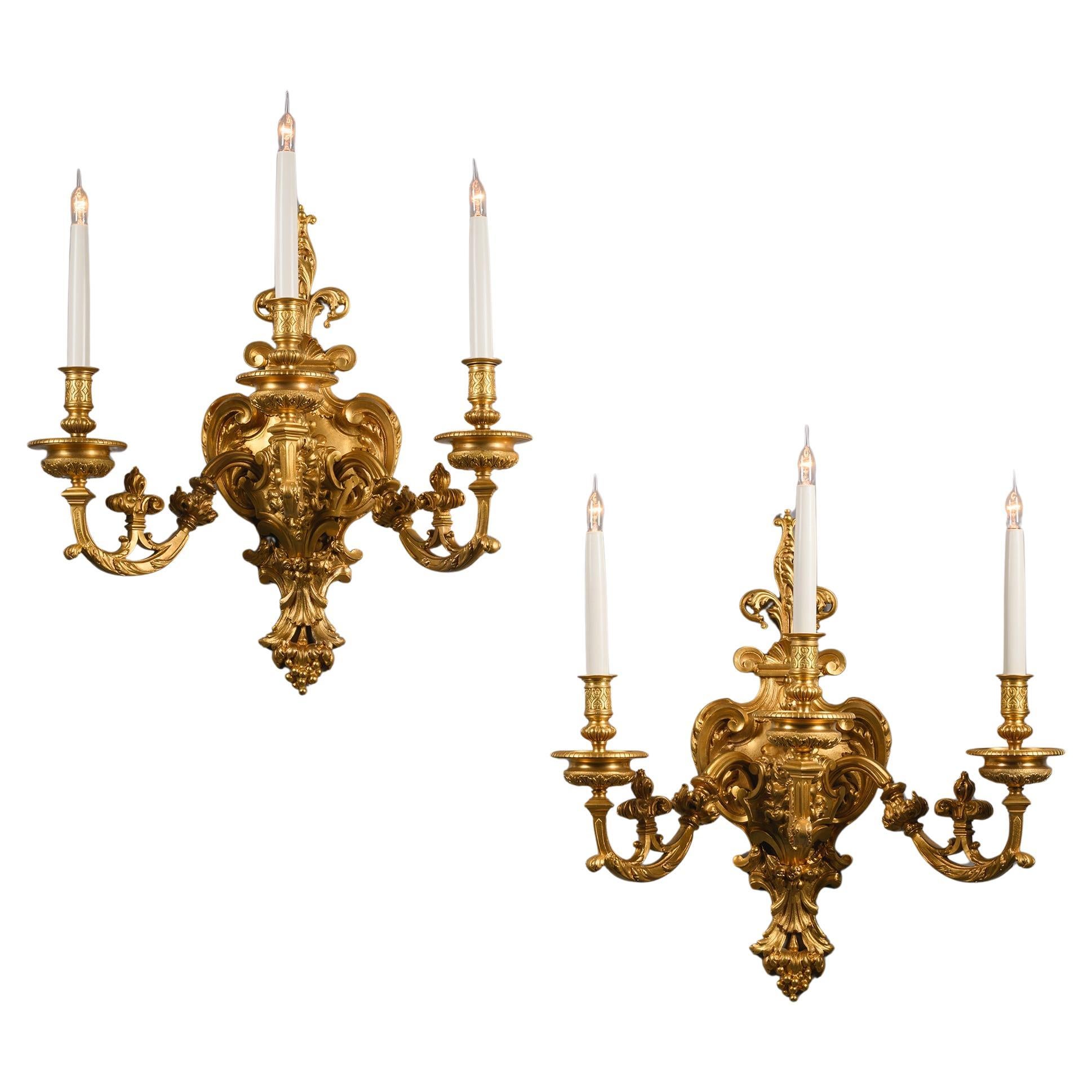 Pareja de apliques de tres luces de bronce dorado