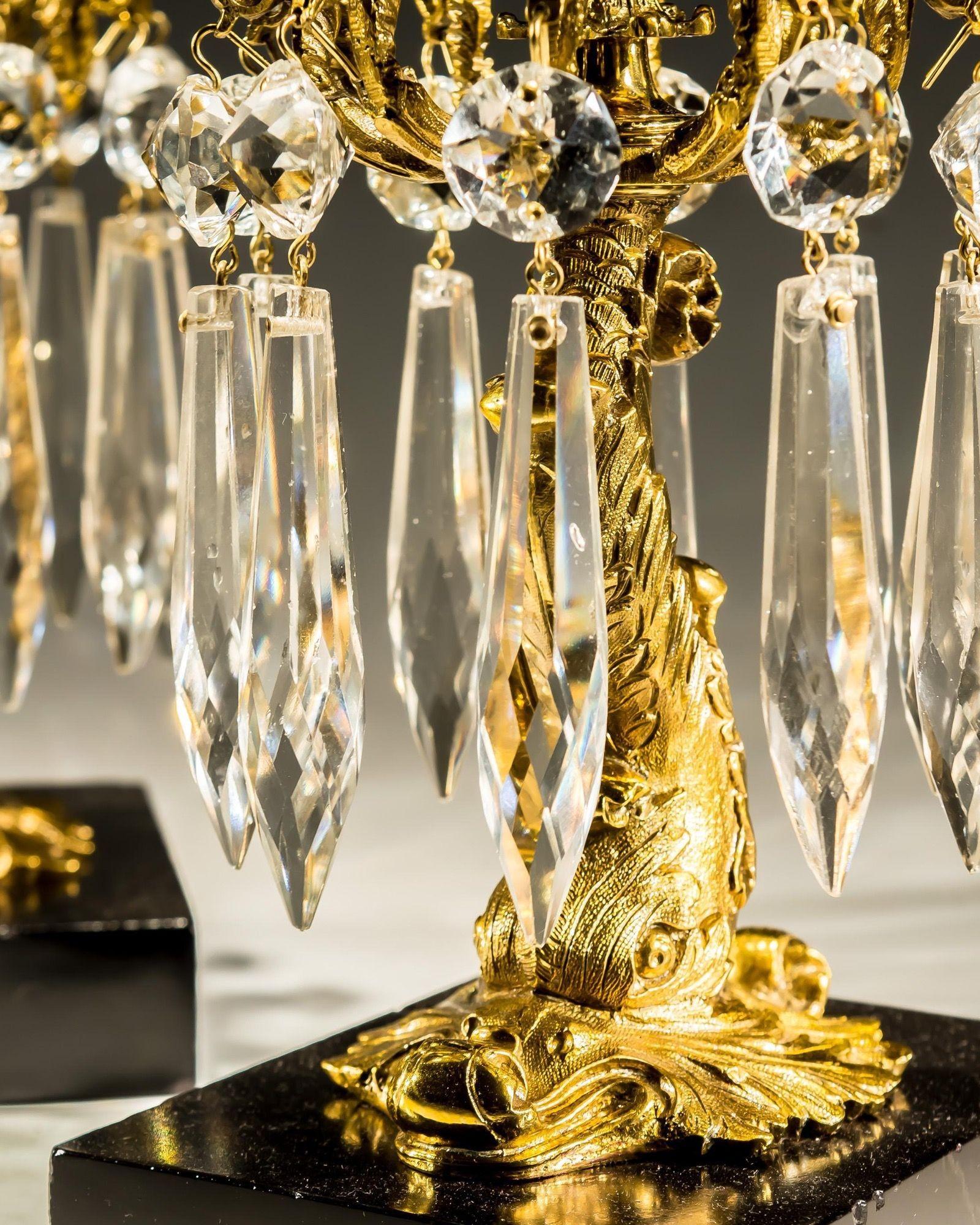 Paire de chandeliers en forme de dauphins en laque dorée suspendus à des gouttes de glaçons sur des bases rectangulaires en marbre noir.