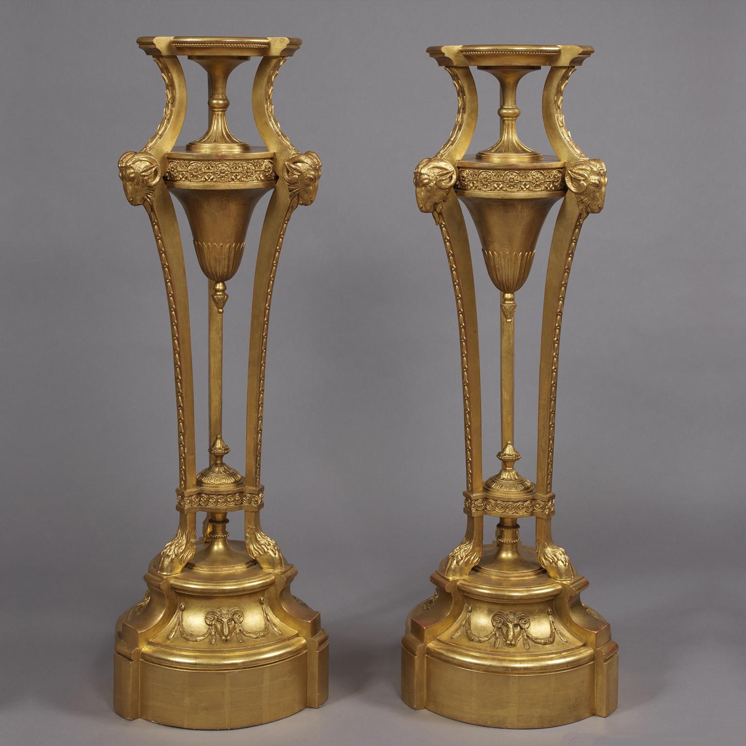 A pair of giltwood and Gesso pedestals, in the manner of Robert Adam. 

Each pedestal having a circular top with a waisted fluted socle, on ram's-mask headed acanthus-carved fluted monopodia, raised on a tiform-plinth with lion's paw feet.