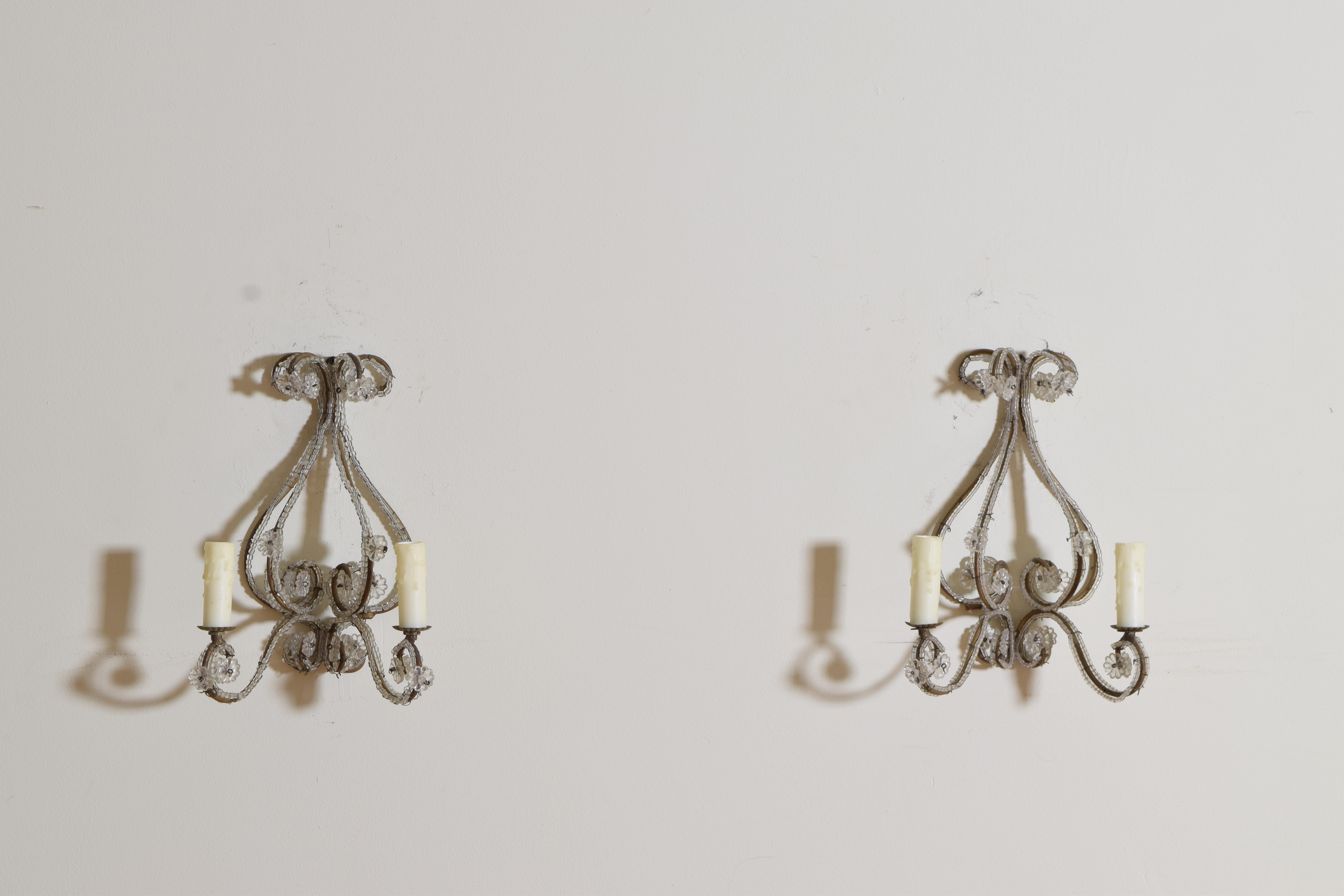 Each lyre shaped sconce constructed of scrolled gilded iron and wrapped in glass bead chain, the frames issuing two curved arms