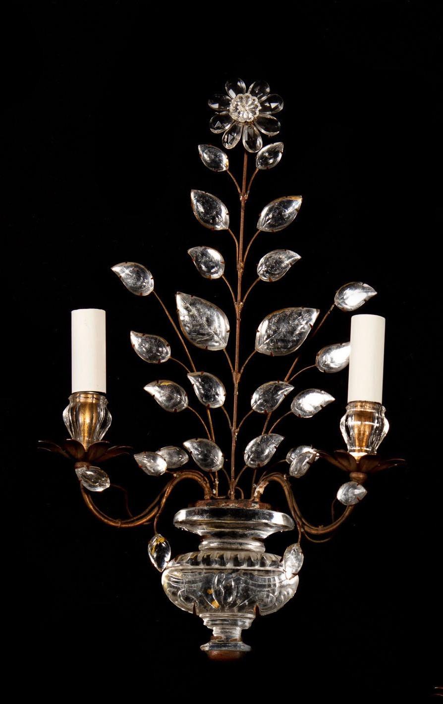This stylish pair of glass and gilt metal wall lights fashioned as urns sprouting foliage and surmounted by a flowerhead are attributed to Maison Baguès and date from the mid-20th century and accordingly are wired for electricity. The French design