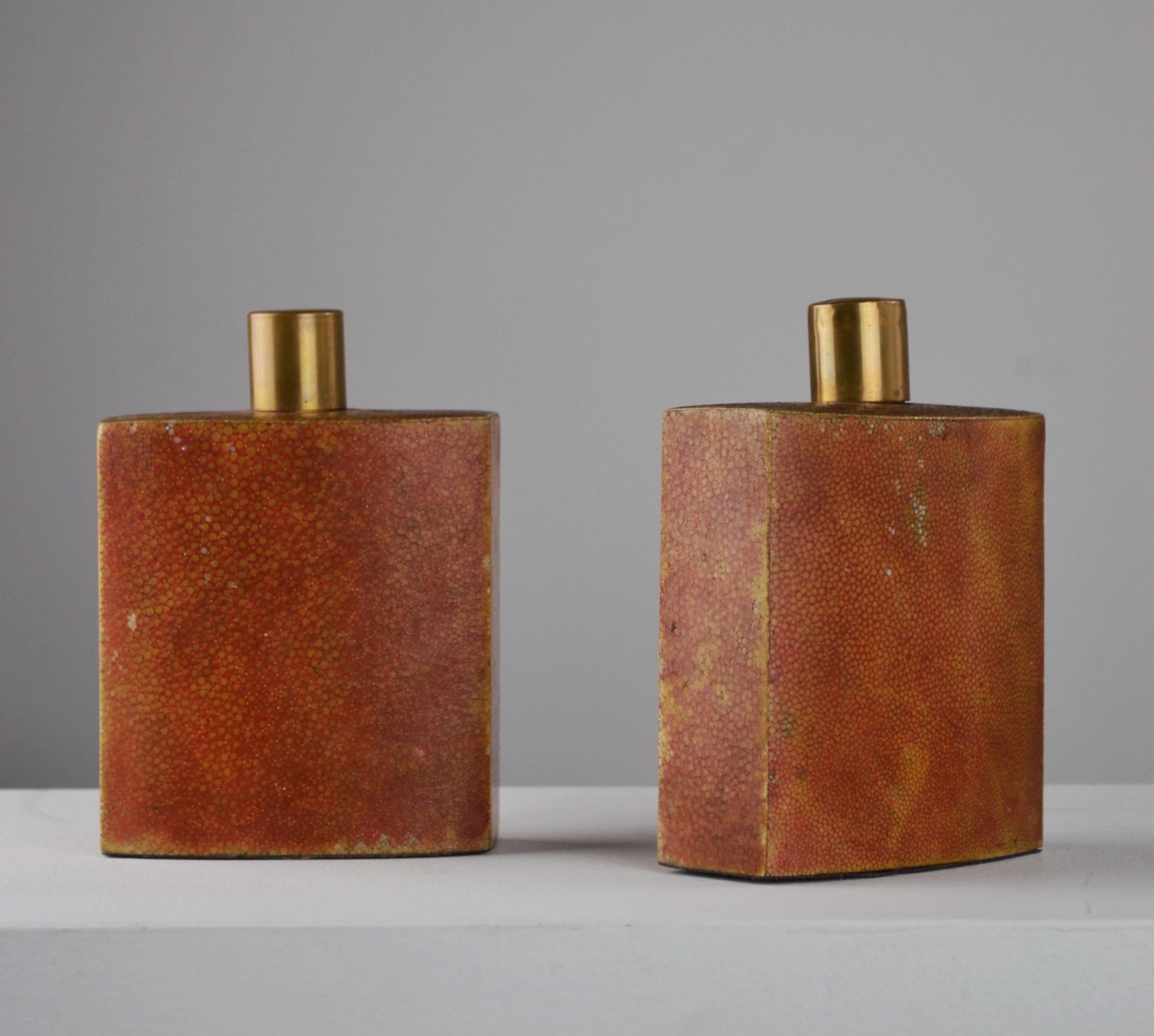 A stunning pair of glass perfume bottles, covered in shagreen, with glass stoppers and brass over-caps, dating from the 1930s. In the spirit of Jean-Michel Frank's creations, these refined pieces embody the understated elegance and discreet luxury