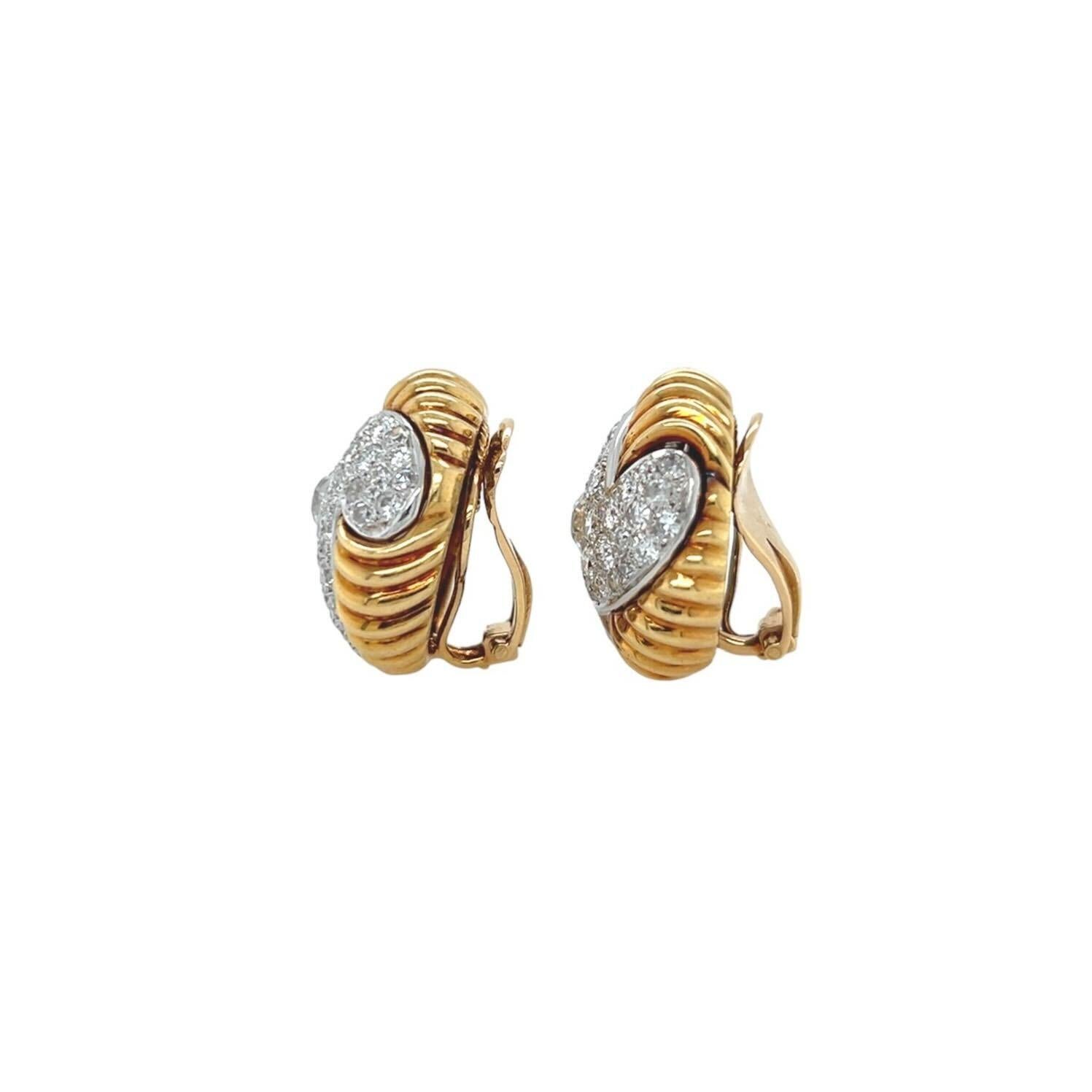 A pair of 18 karat yellow and white gold and diamond earclips.  Each button style earclip designed as a stylized white gold pinwheel motif pave set with approximately fifty one (51) round brilliant cut diamonds, filled in around the pinwheel by