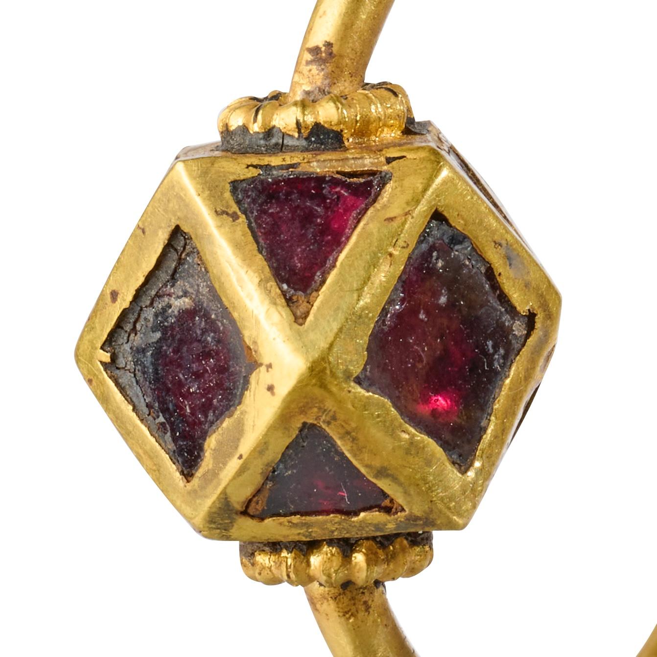 Paire de boucles d'oreilles polygonales en or et grenat
 
Ostrogothique, vers le VIe siècle après J.-C.
 
Mesures
• 3,2 × 2,9 × 1,2 cm et 3,1 × 3 × 1,2 cm
• Poids : 10,7 grammes chacun
 
De forme circulaire, chaque boucle d'oreille est composée d'un