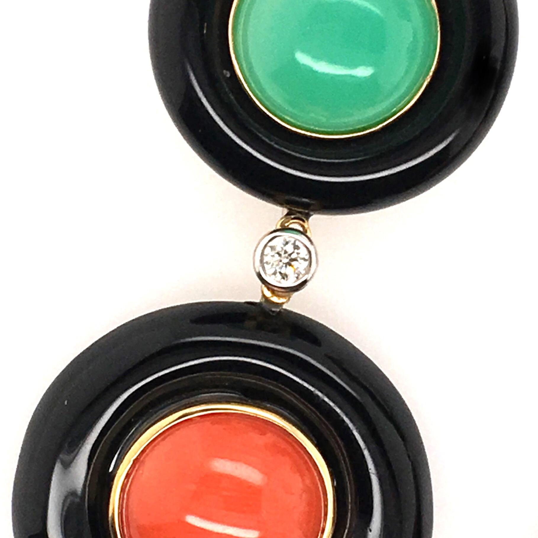 A pair of 18 karat yellow gold, black onyx, turquoise, chrysoprase, coral and diamond earrings with collapsible post and omega back.  The earring is composed of bezel-set colored stone cabochons set into three graduated black onyx circular frames. 