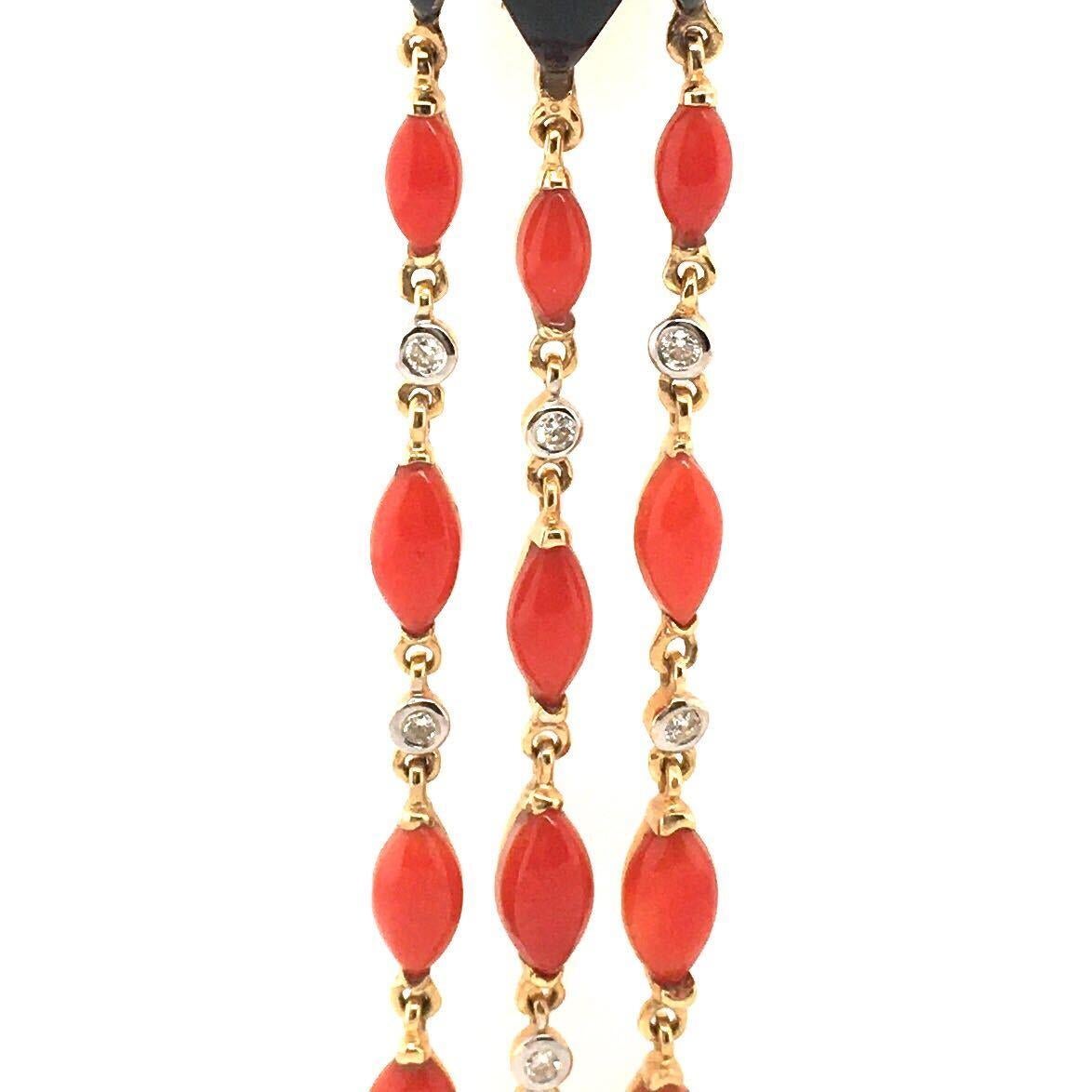 A pair of 18 karat yellow gold, orange-red coral, black onyx and diamond dangling earrings with collapsible posts & omega backs.  Each earring suspends three line pendants, each  set with five coral navettes and two circular cut diamonds, all joined