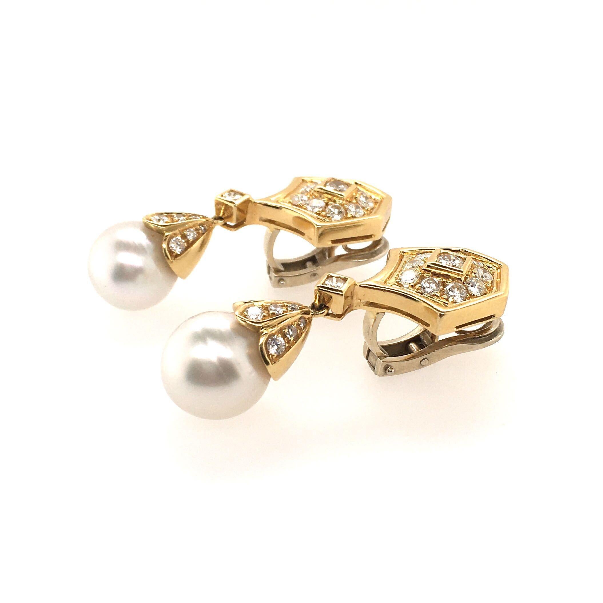 A pair of 18 karat yellow gold, diamond and pearl earrings. Designed as a shield shape set with circular cut diamonds, suspending a drop shaped pearl, measuring approximately 12.4 and 12.6mm, from a pave set diamond cap. Forty (40 ) diamonds weigh