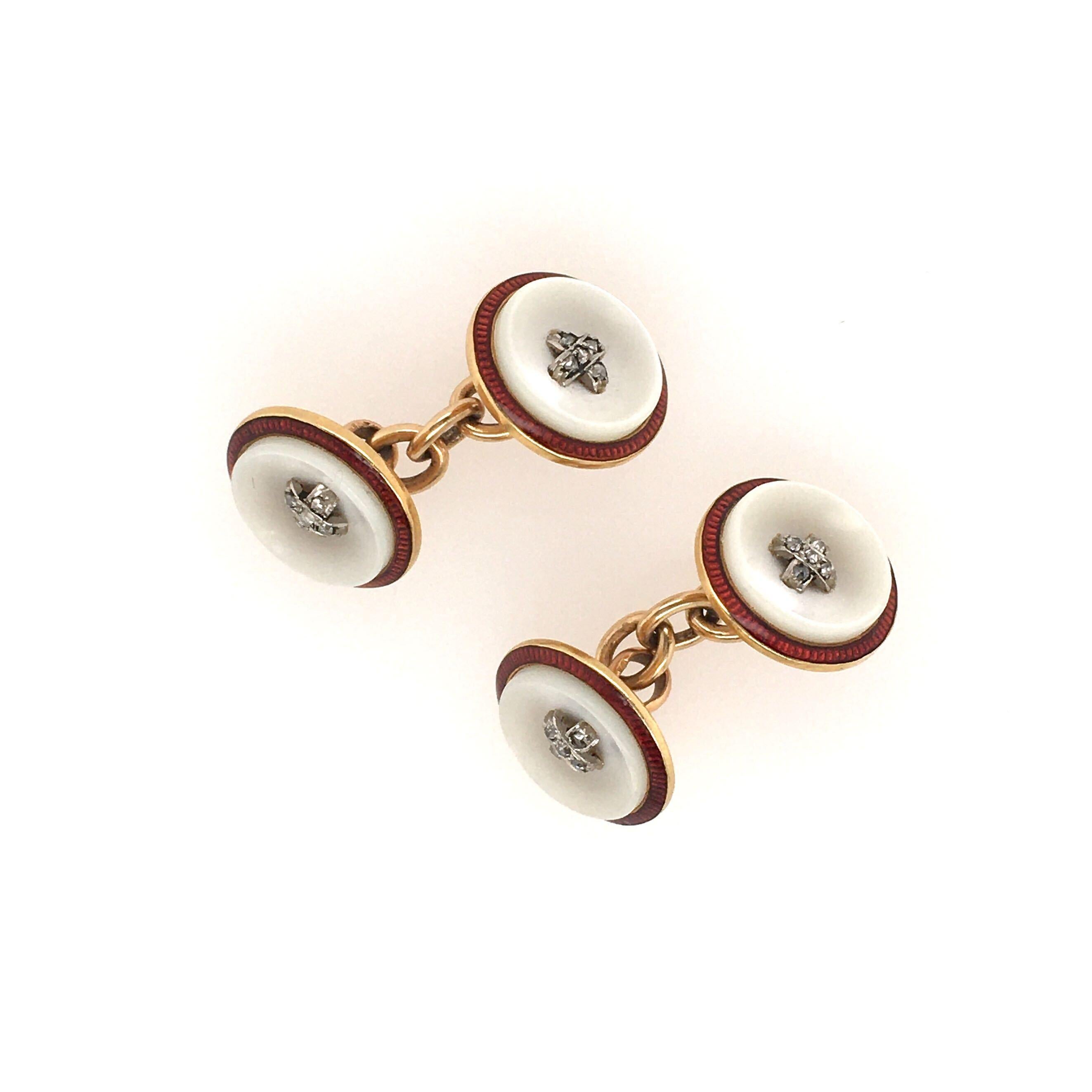 A pair of 18 karat yellow gold, mother of pearl, diamond and enamel cufflinks. Each double link designed as a mother of pearl button, enhanced by pave set diamonds, with red enamel trim, joined by a chain. Diameter is approximately 1/2 inch, gross