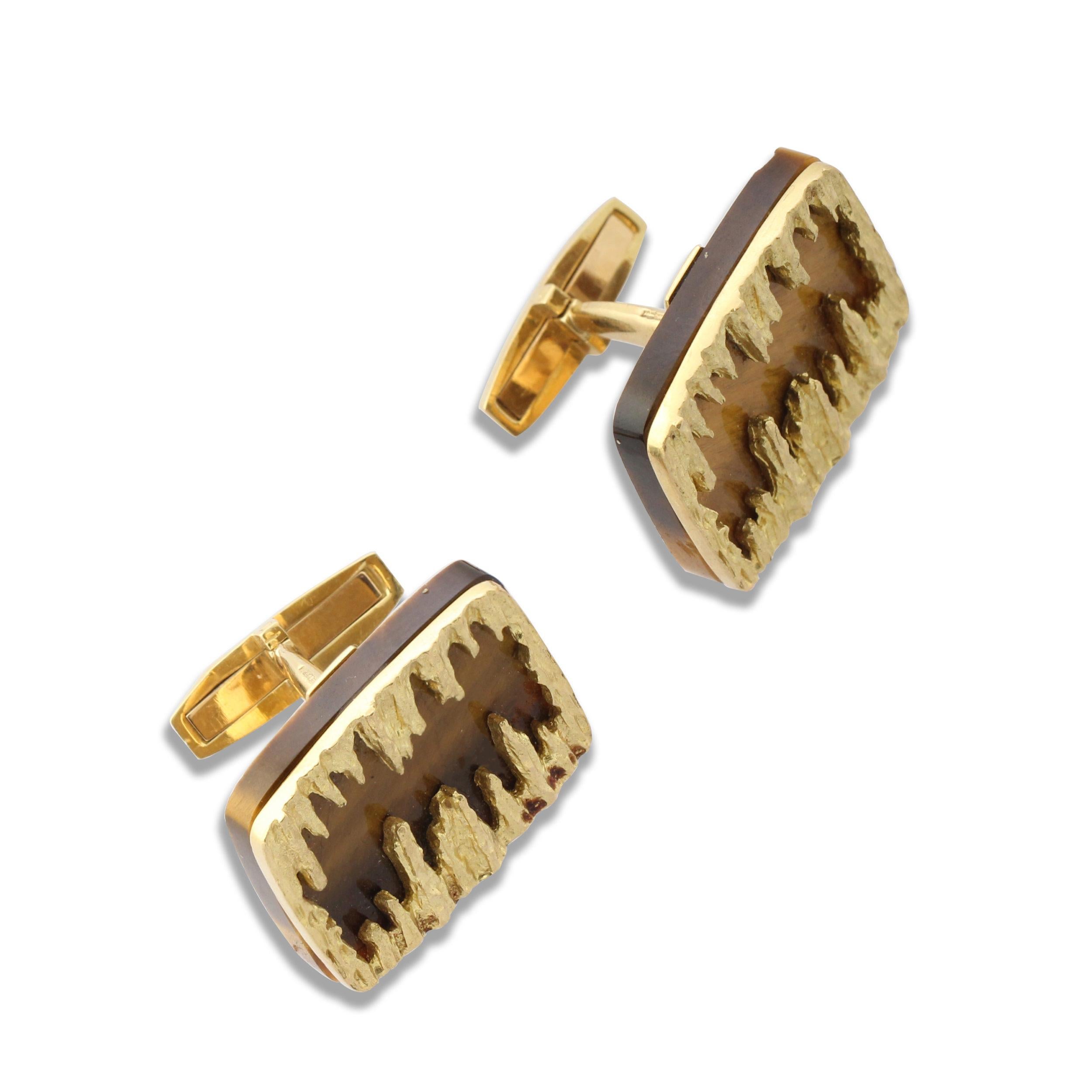A pair of 18k gold rectangular cufflinks by Grima set with a panel of tiger’s eye quartz beneath an abstract textured gold mount. Circa 1970s.