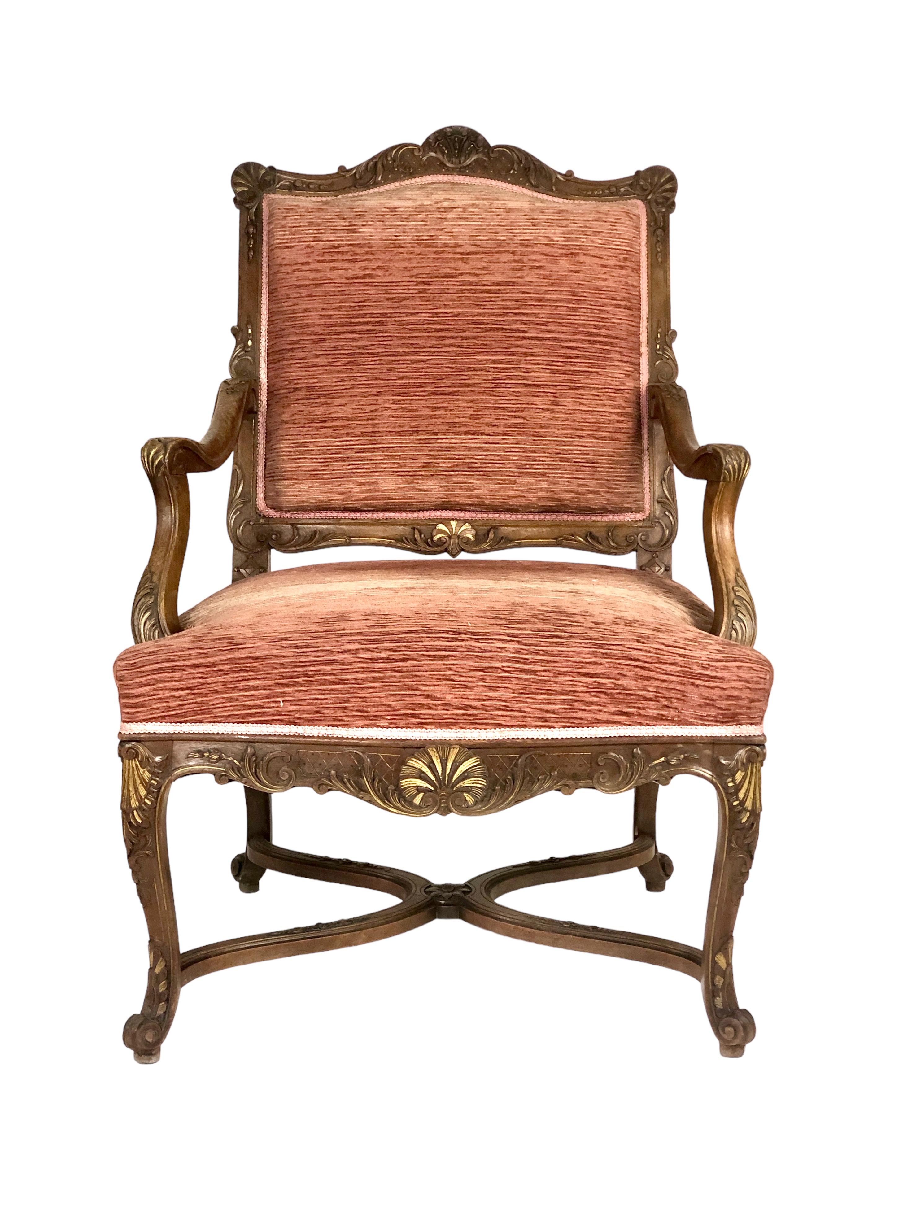 Une belle paire de fauteuils de style Régence en noyer mouluré et sculpté, garnis de velours de terre cuite. Bien que très similaires, ces chaises ne sont pas tout à fait des paires identiques. De tailles légèrement différentes, l'une est ornée d'un