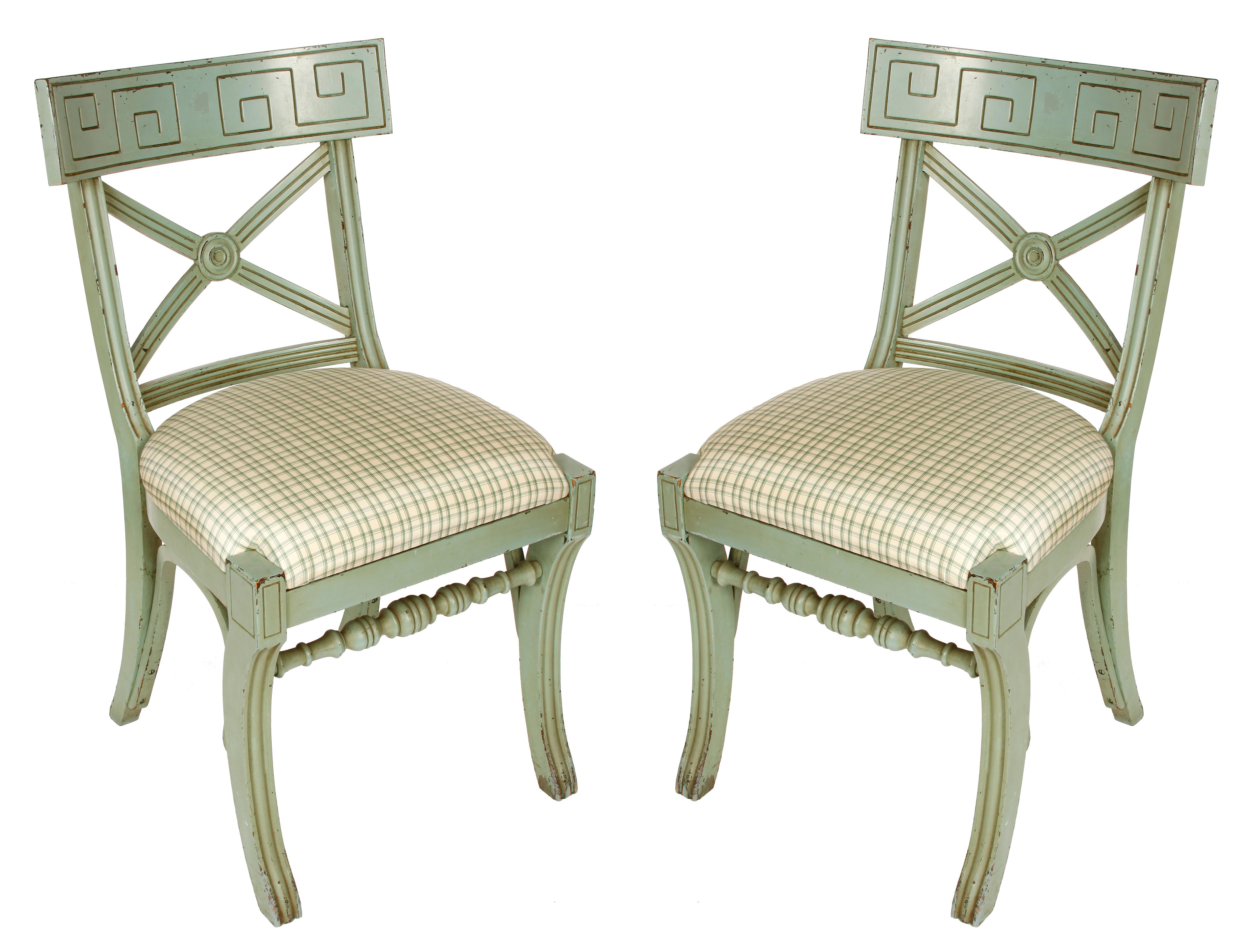 A pair of vintage Greek key painted Empire style X-back side chairs with newly upholstered silk check cushions. Curved and turned accents to chair legs.