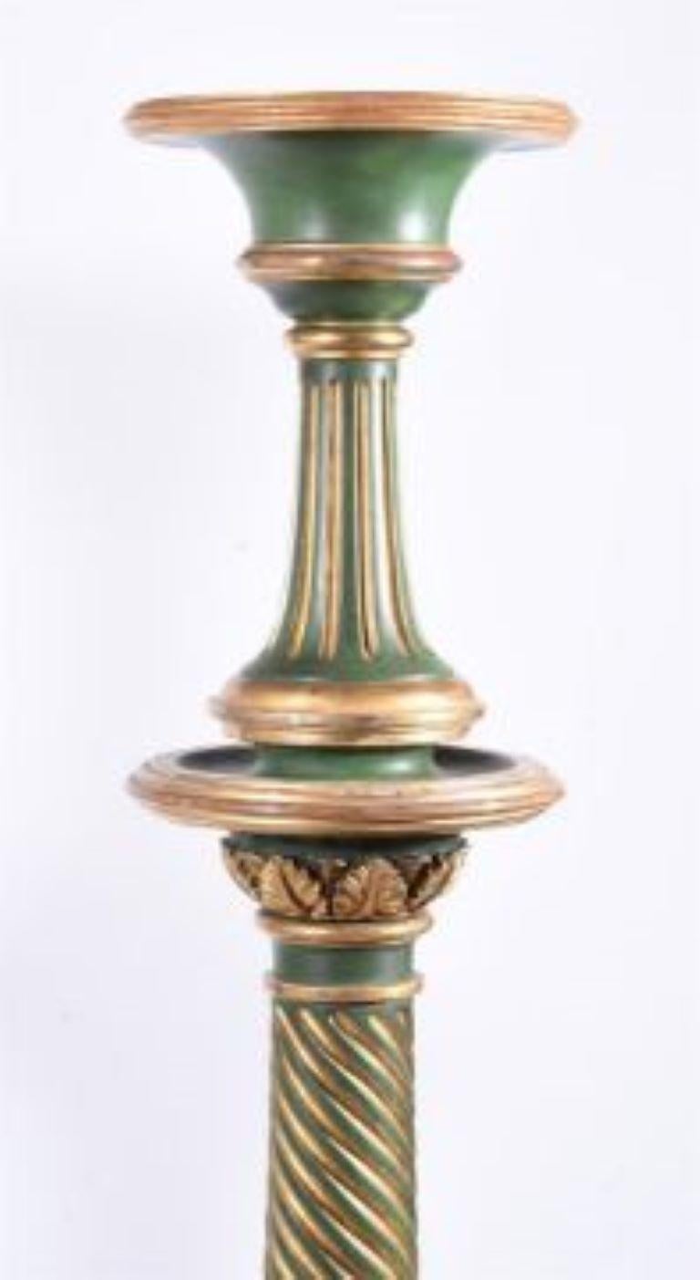A PAIR OF GREEN PAINTED AND PARCEL GILT TORCHERES19TH CENTURY, IN THE GEORGE IV Styleeach with turned top on a spirally fluted baluster shaft, on a concave-sided tripod base with a flowerhead, on ball feet149cm high, 42cm diameter.