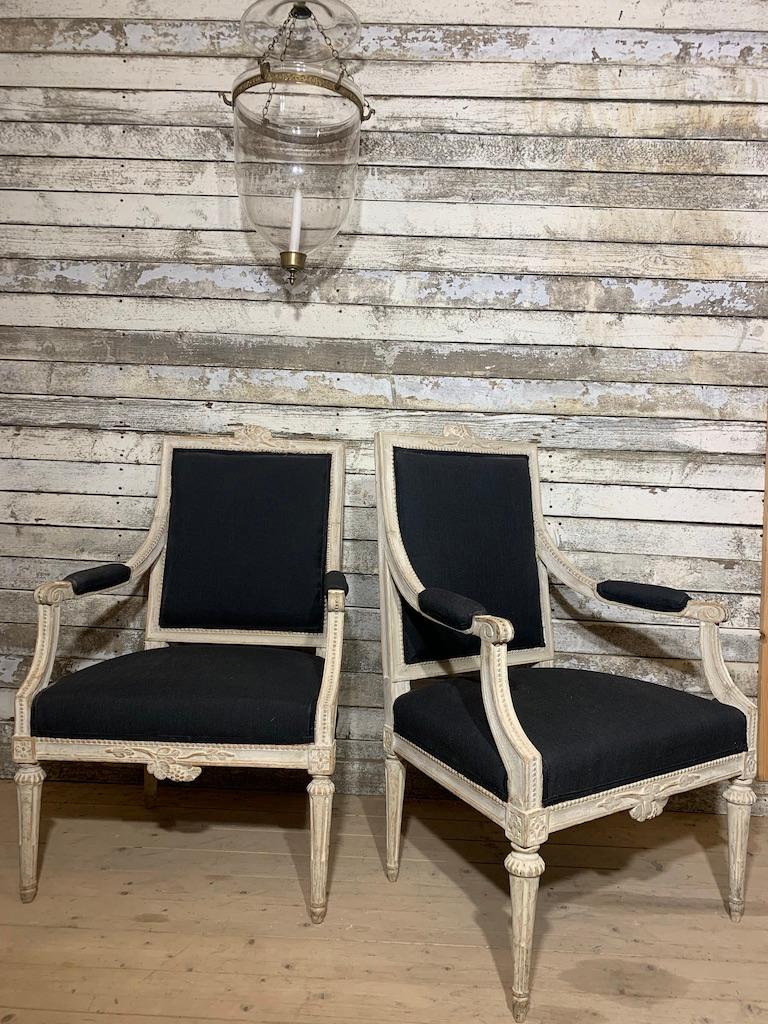 A pair of Gustavian armchairs made in Sweden, Stockholm around 1780. The chairs have a rectangular back with two open, padded arms. They are hand carved in shapes typical for the Gustavian period with floral and leaf motif at the back and seat