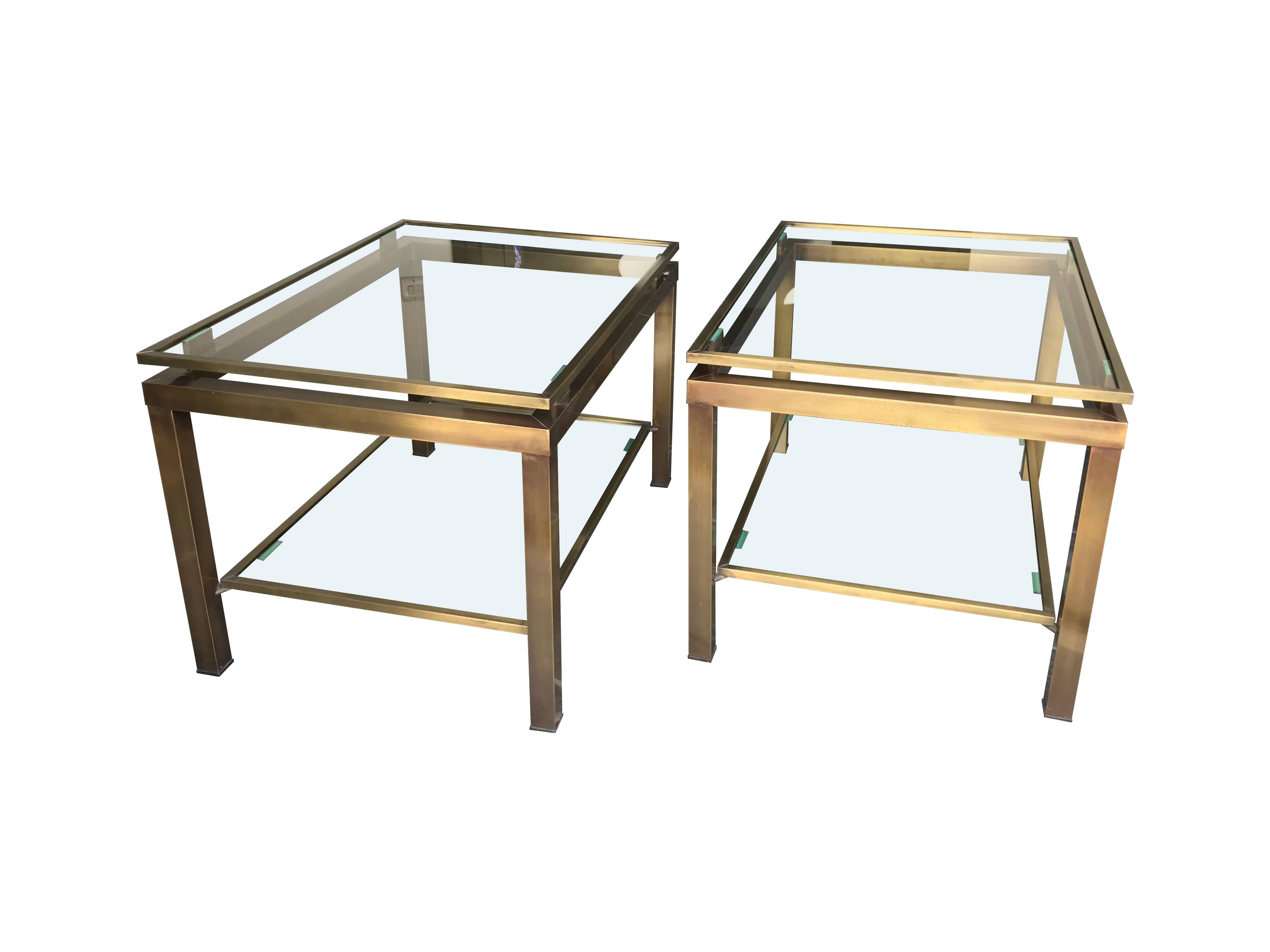 A pair of Guy Lefevre side tables in gilt metal with two glass shelves and signature floating top shelf.