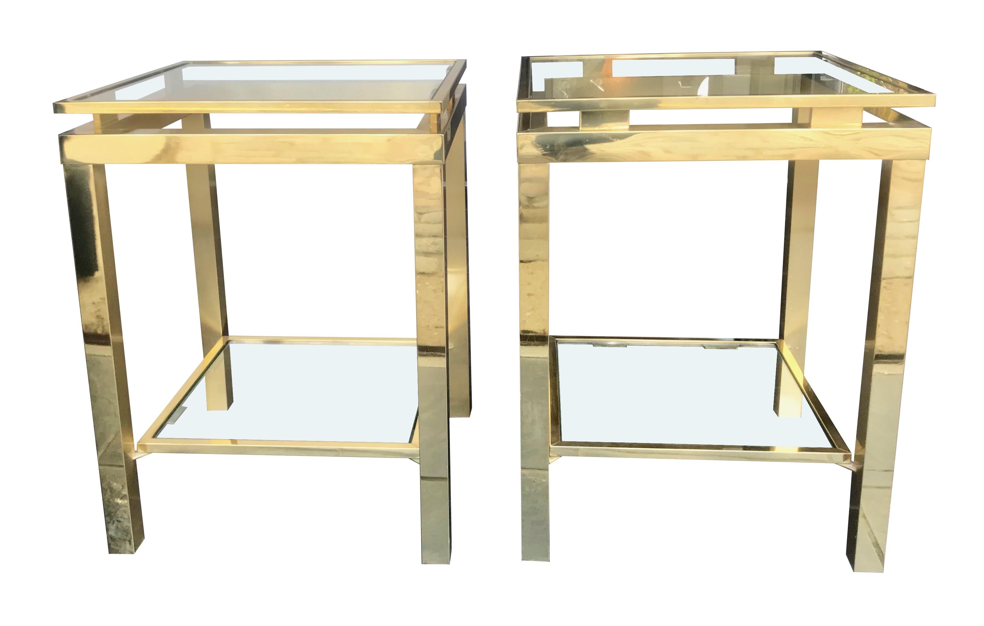 A pair of Guy Lefevre style, polished gilt metal side tables with each with 2 clear glass shelves.