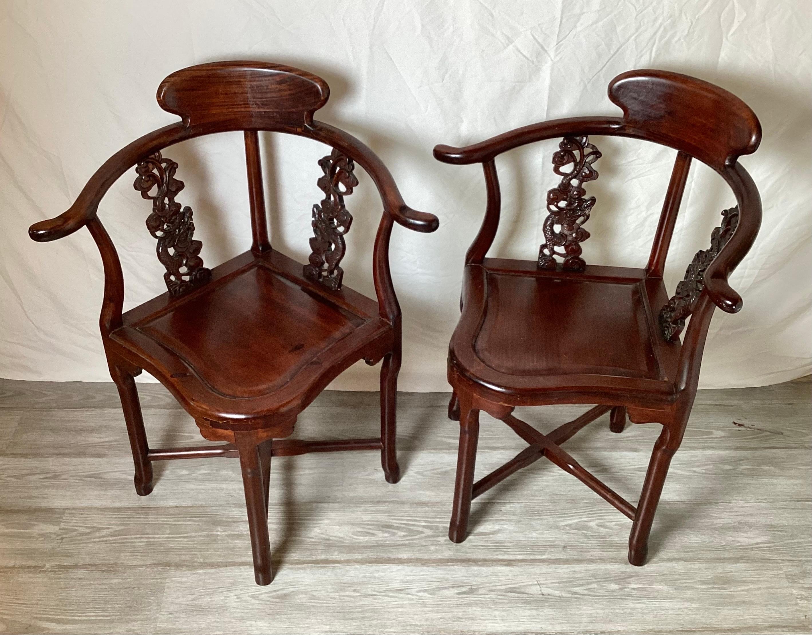 A pair of nicely carved Chinese Hung Mu Wood 2-way corner arm chairs. WIth rounded backs with hand carved dragon motif splats, Mid 20th Century.