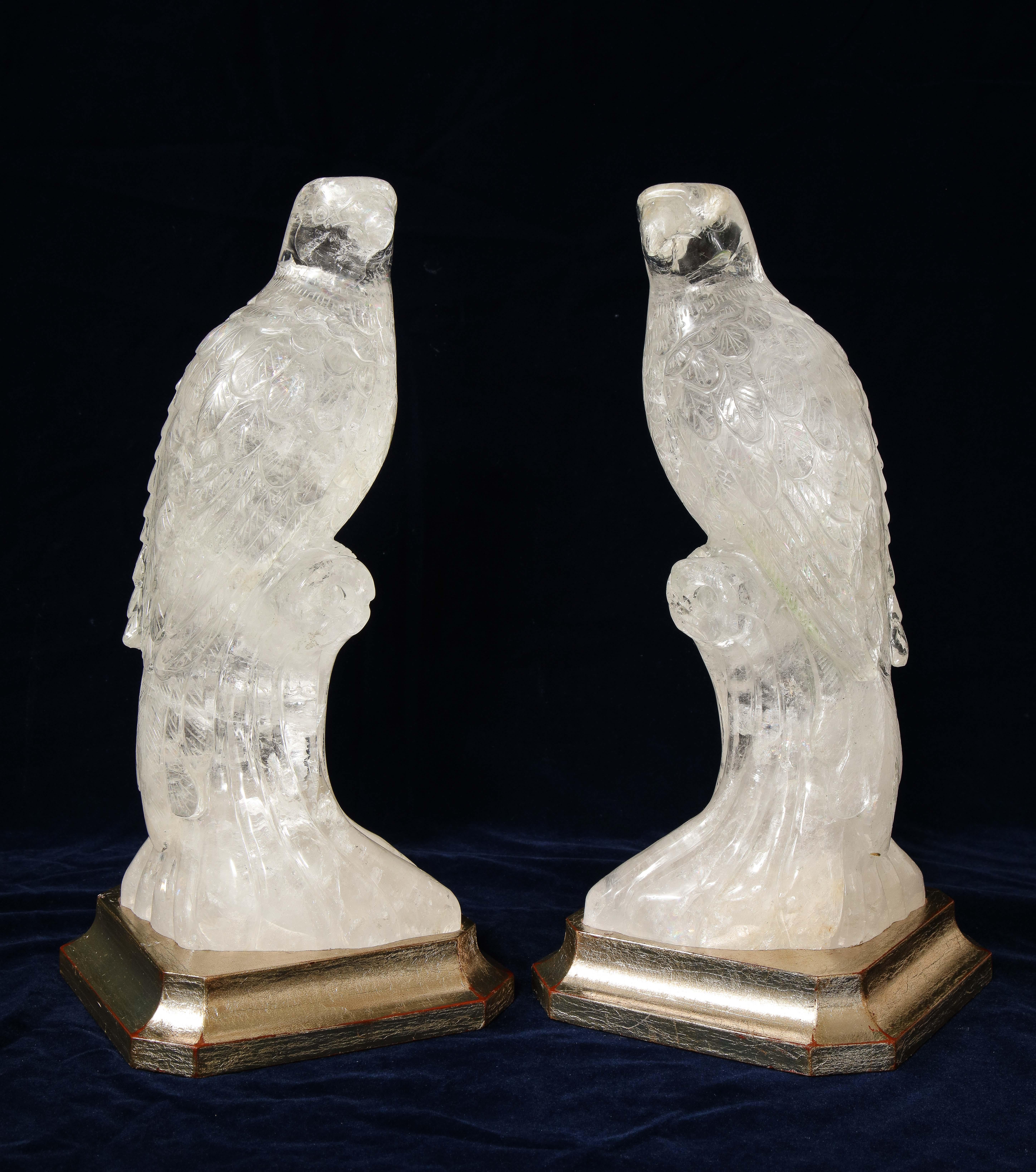 A beautiful pair of hand carved and hand-polished clear rock-crystal quartz parrots on silver-gilt bases. Each is beautifully hand carved and further hand-polished with meticulous detail and craftsmanship. Each parrot is naturalistically resting on