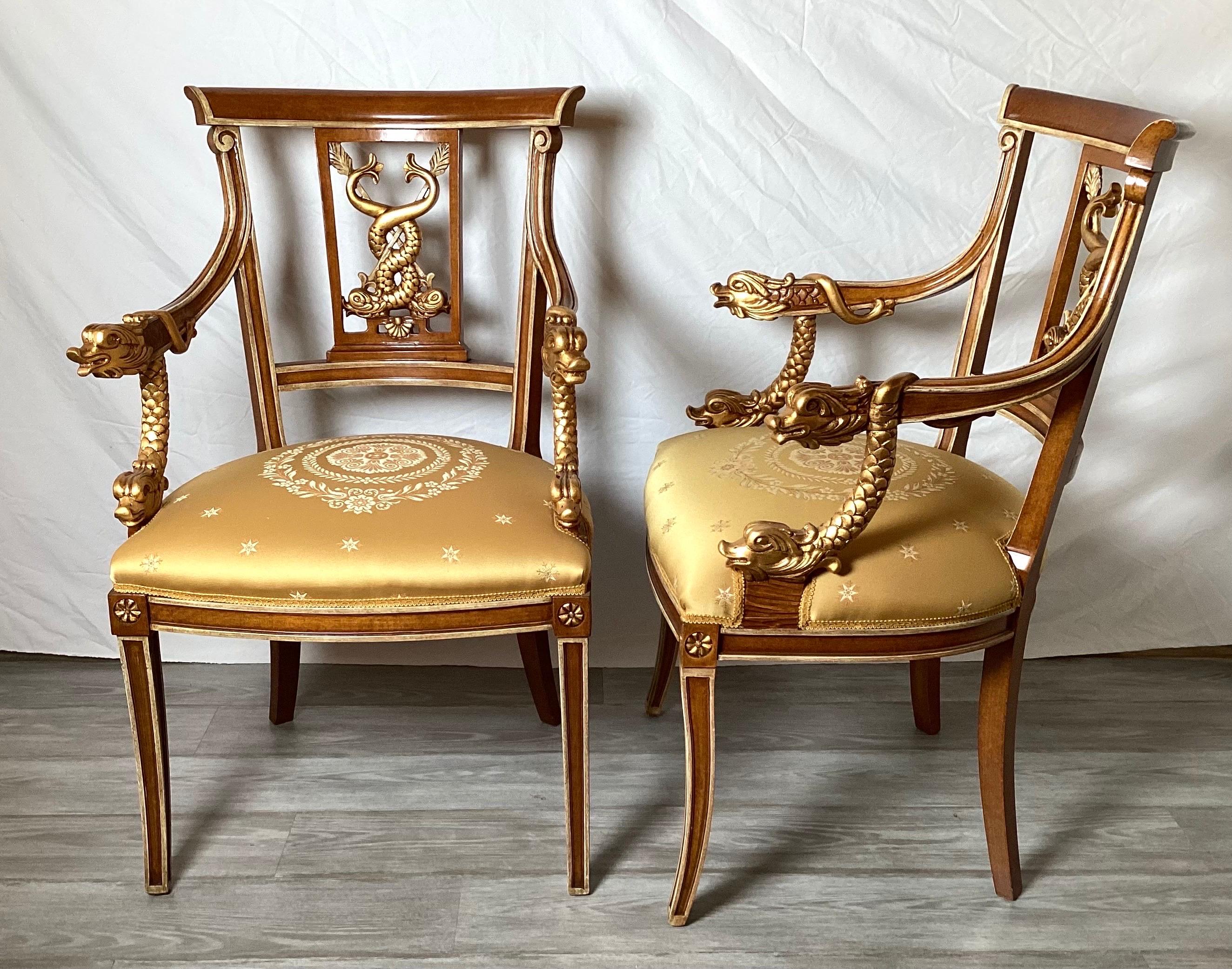 An elegant pair of hand craved neoclassical armchairs with gilt decoration. Made in Italy by Galimberti Lino. The back and arms with a dolphin motif with gilt trim all around the frames. The seats with a gold damask medallion.