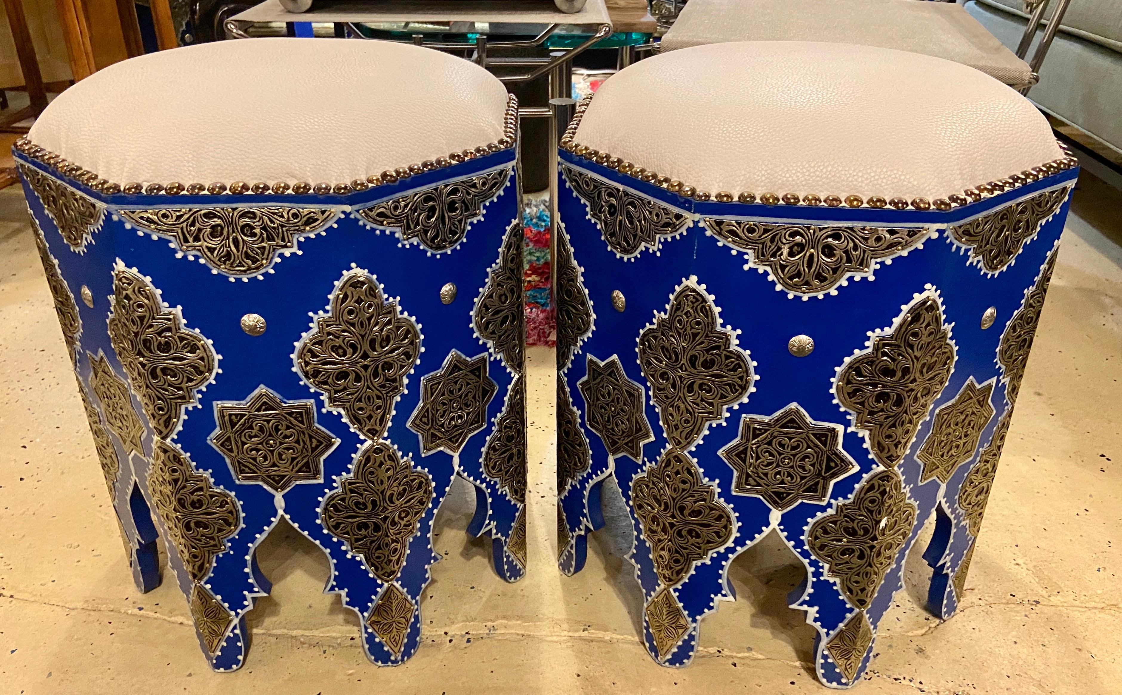 Moroccan Blue Stool or Ottoman with White Leather Top, a Pair  
This exquisite pair of handmade Moroccan stools will add unique style and sophistication to any room. The pair is hand painted blue and features expert silver metal filigree work and