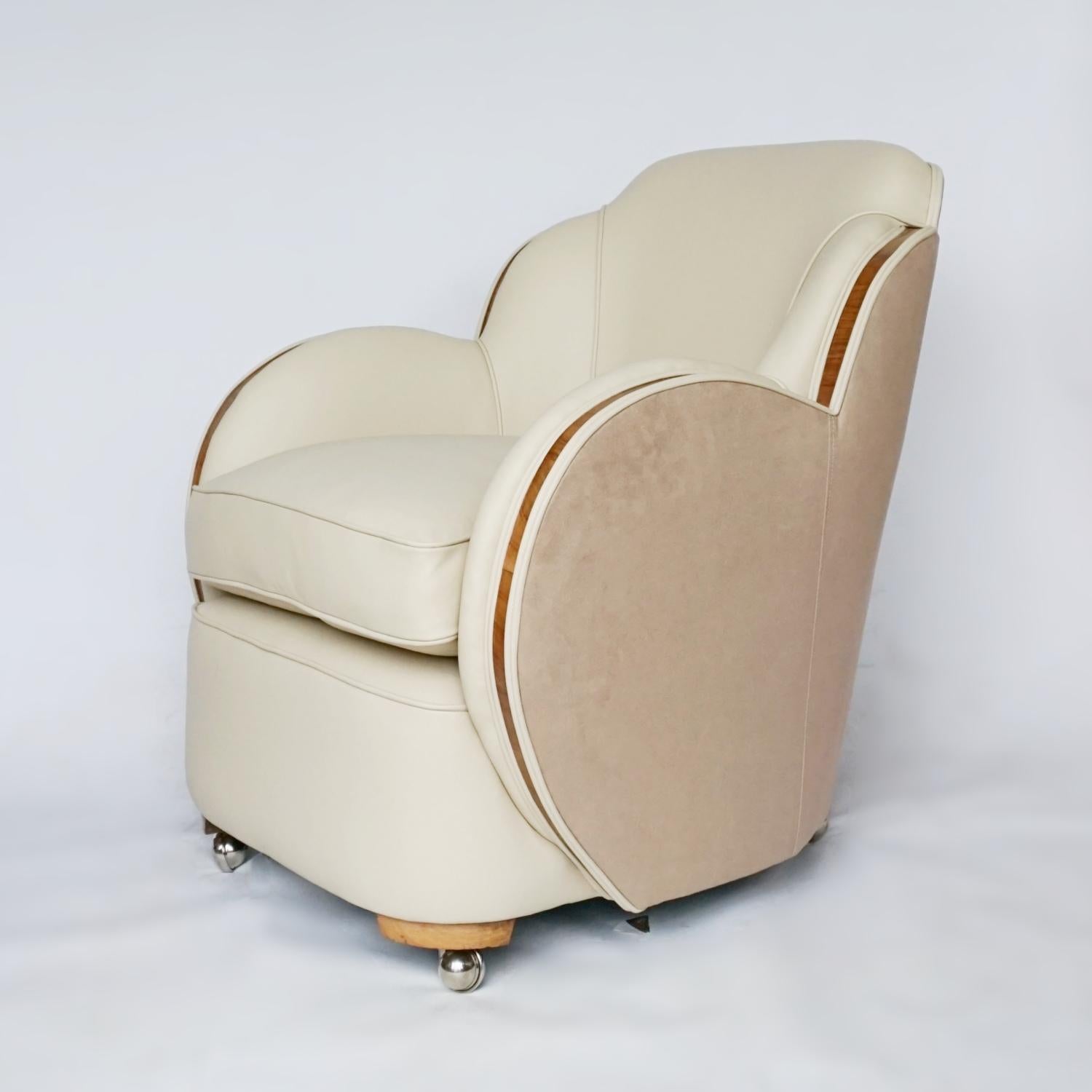 A Pair of Art Deco Cloud chairs by Harry & Lou Epstein. Re-upholstered in cream leather with a contrasting faux suede to sides and back. Figured walnut banding to the sides. Replacement casters. 

Dimensions: H 84cm W 72cm D 65m Seat H 50cm D