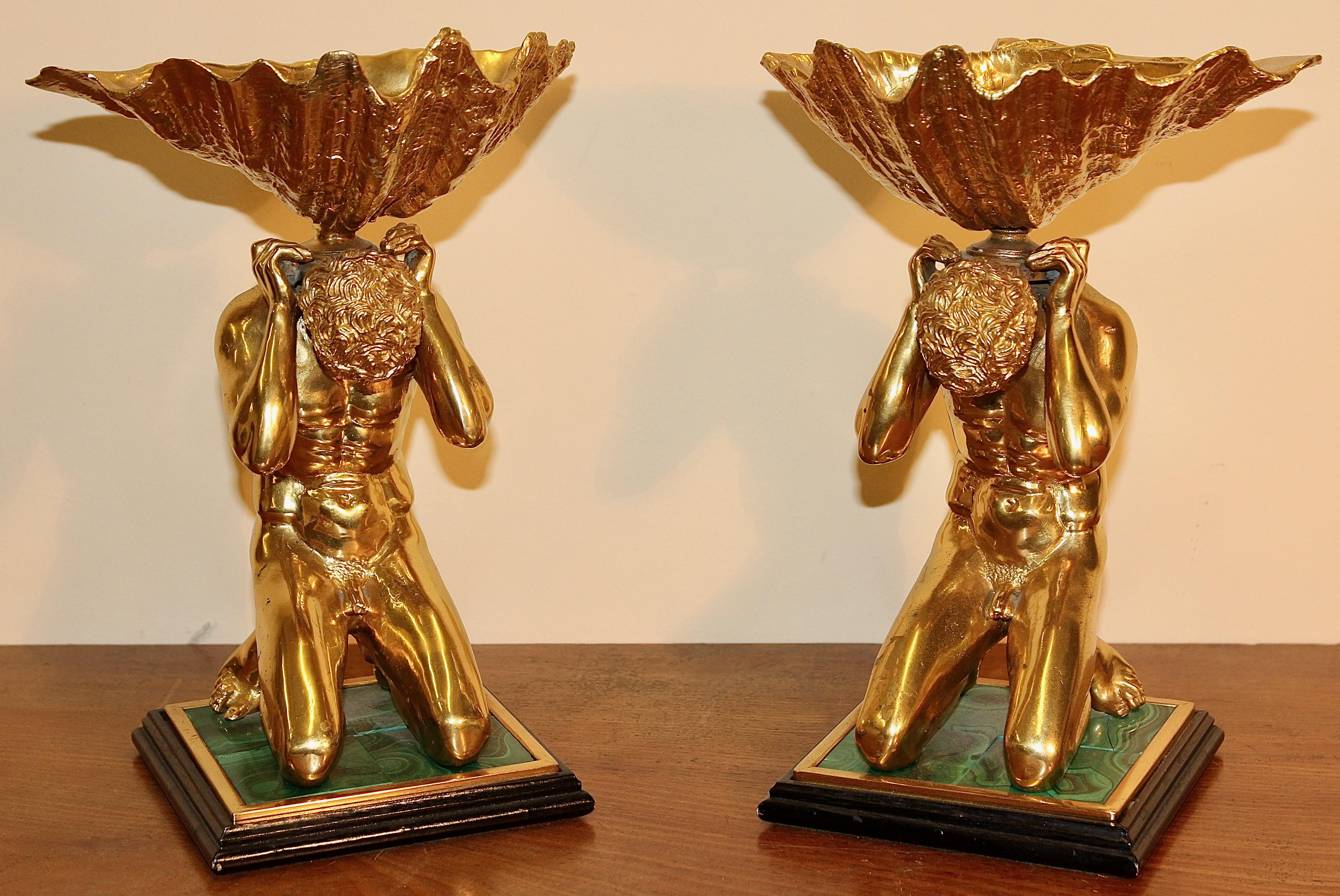 A pair of heavy, decorative bowls. Two kneeling acts, gilded, on malachite base.

Figures and shells made of gilded metal.

Base with malachite tiles.