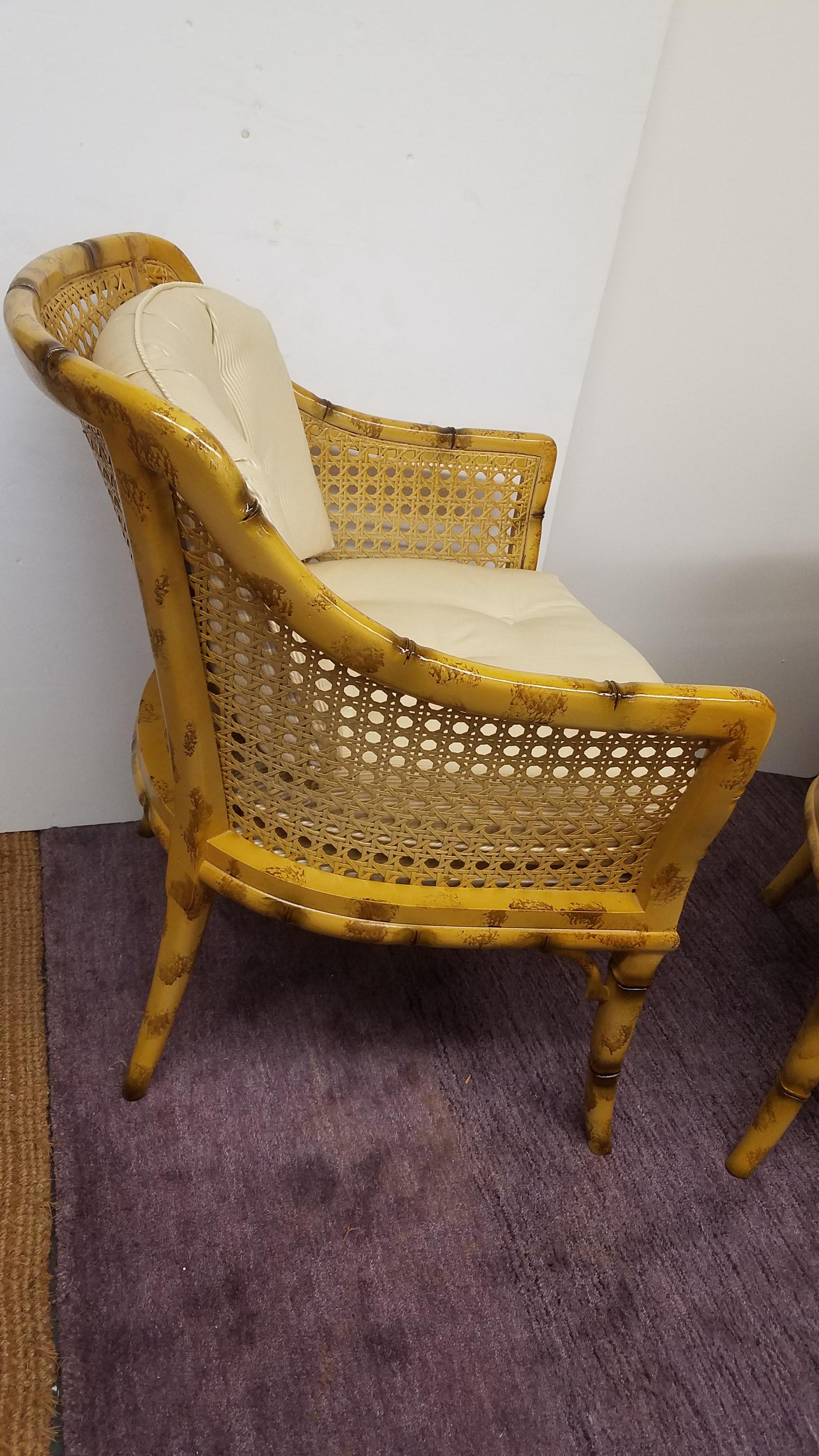A wonderful pair of faux painted bamboo motif Armchairs with a glossy light tortoise finish. The sturdy frames with caned back and sides with cushions in an ivory cream subtle pinstripe. Excellent condition and high quality, attributed to Baker