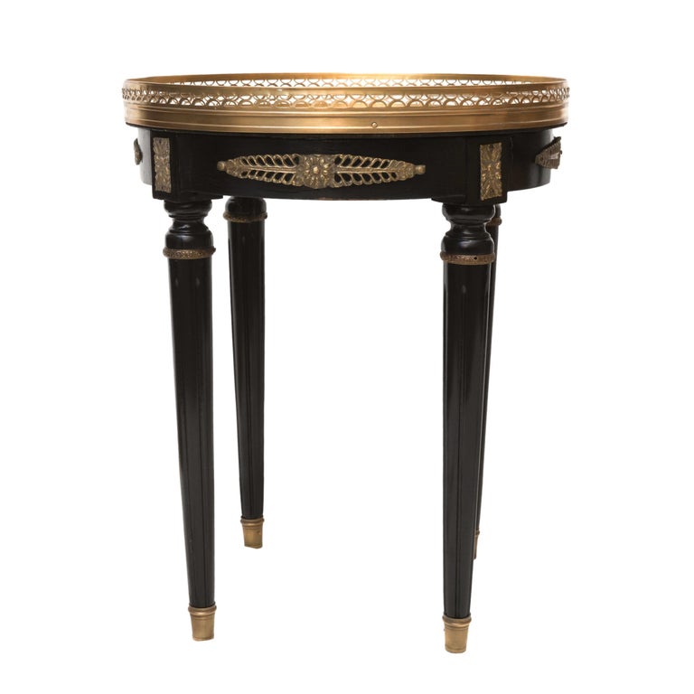 A Pair of Hollywood Regency Style Black Lacquered Side Tables, France 1940. A pair of regency style black lacquered side tables with reeded legs and gilded brass mounts and sabots. The top of the tables are sectioned with gold-leafed under glass,