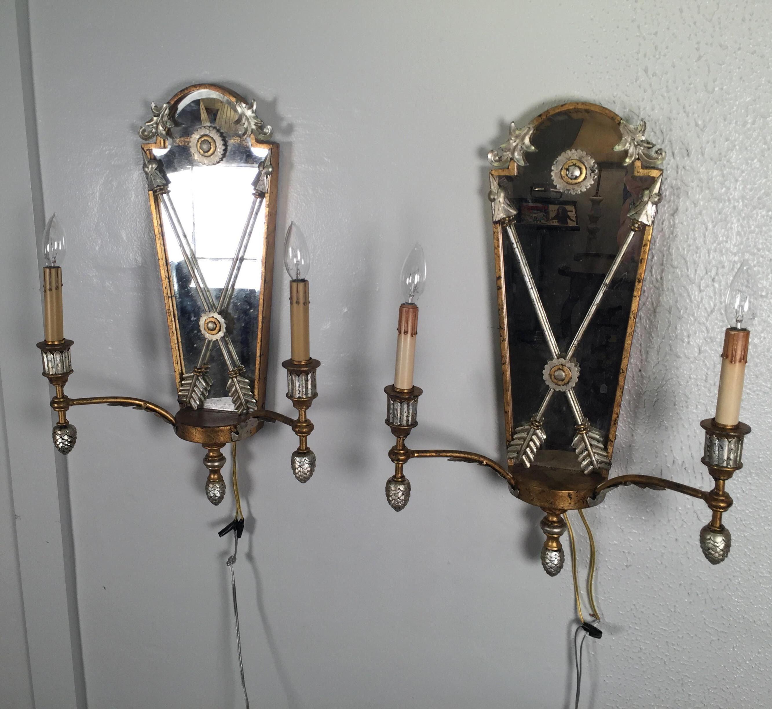 The two light sconces with silver and gold gilt with distressed mirrored backs. The back panels with a neoclassical double crossed swords.