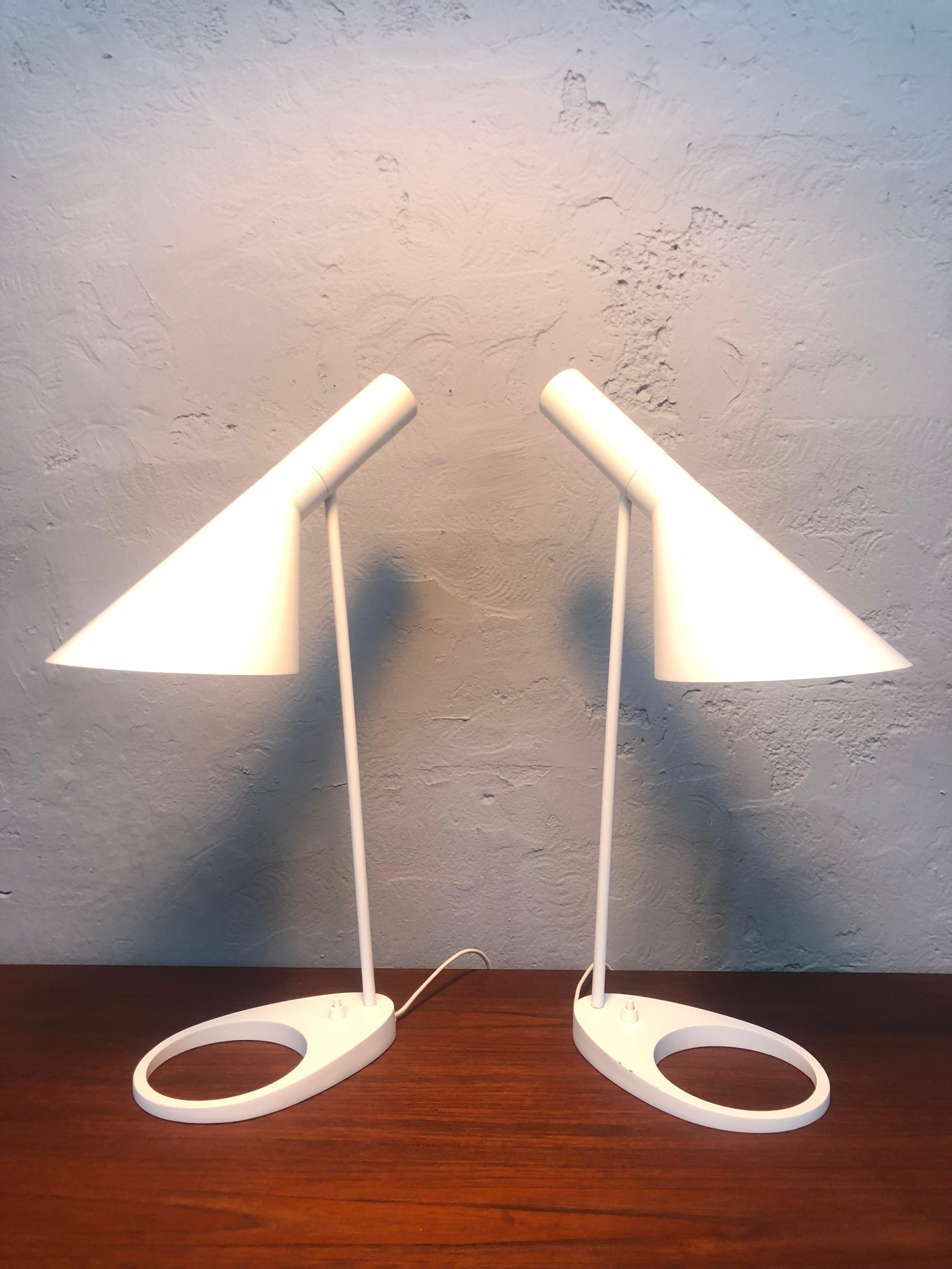 A Pair of iconic Arne Jacobsen table lamps in white from the 1980s. 
This iconic lamp was designed by Jacobsen in 1957 for the worlds first designer hotel in Copenhagen. 
All of the items designed for this project have become design icons such as