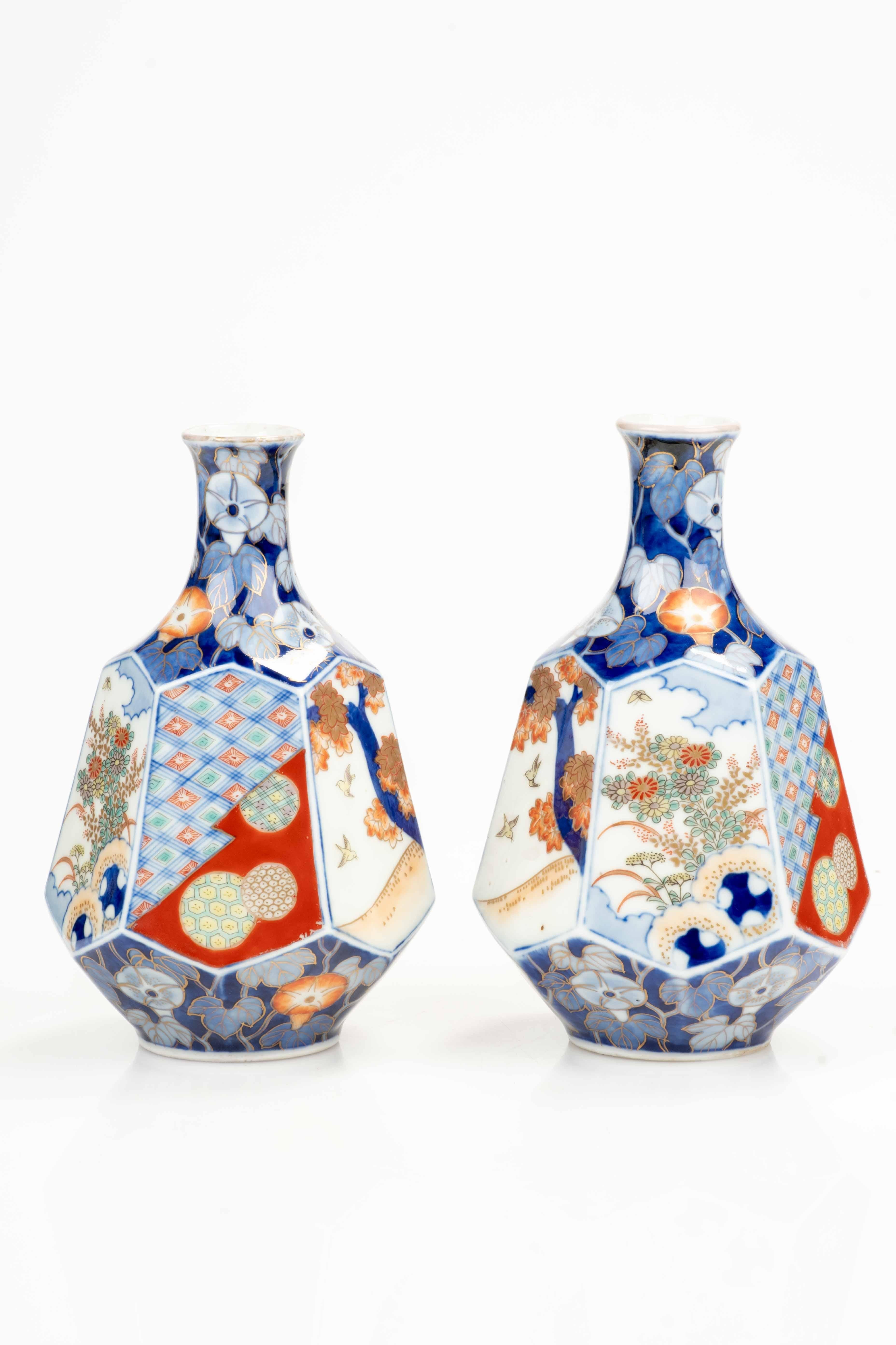 Ein Paar japanische Arita-Porzellanvasen, sechseckig in Pyramidenstumpfform, verziert mit raffinierten naturalistischen und geometrischen Motiven. Die Oberfläche weist die für die Imari-Tradition charakteristische lebhafte Farbpalette auf: Weiß,