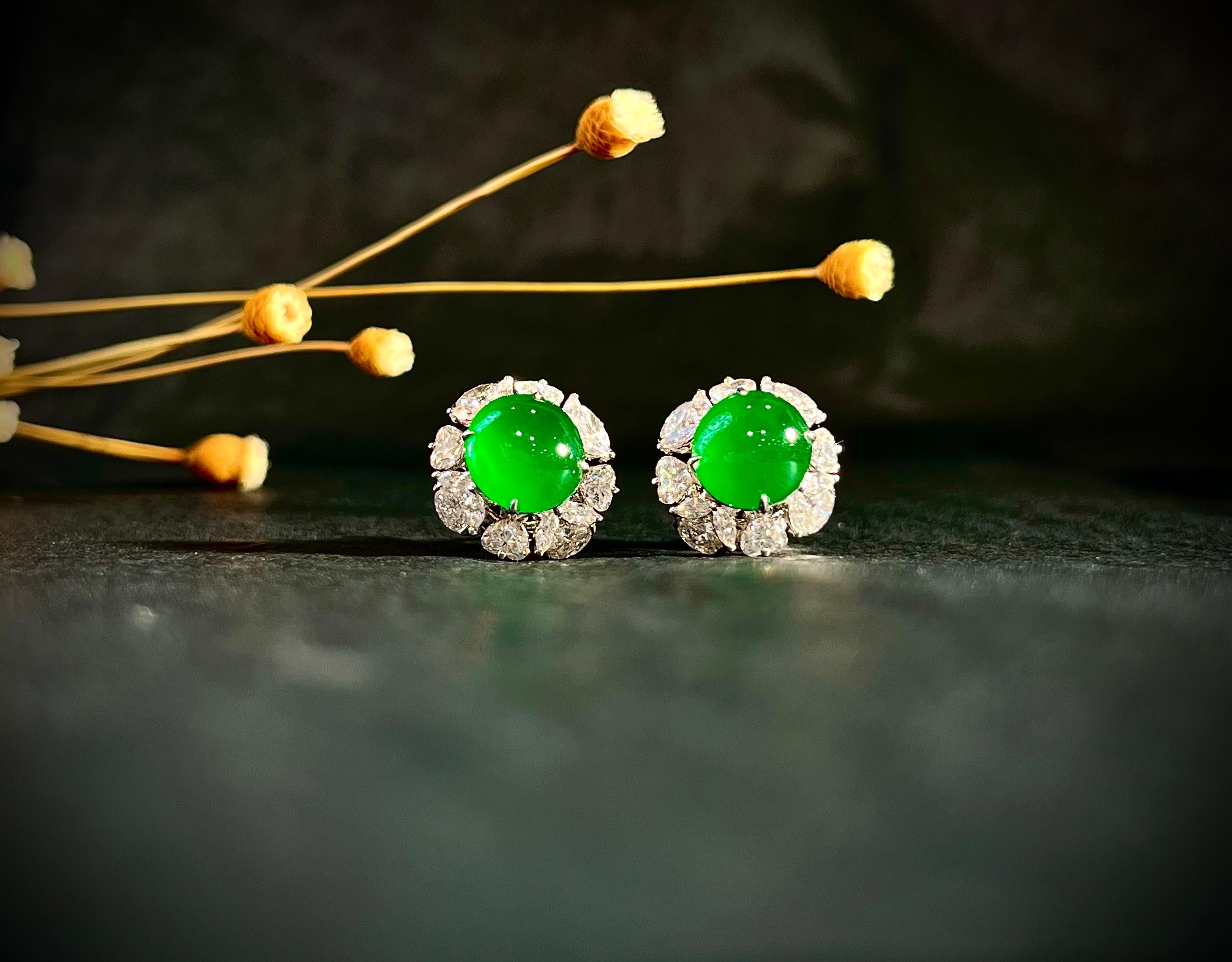 A stunning pair of earrings each set with a highly translucent bright imperial green natural jadeite (Fei Cui) cabochons, decorated with round brilliant-cut diamonds, totaling 0.201 carats, marquise brilliant-cut diamonds, totaling 0.842 carats, and