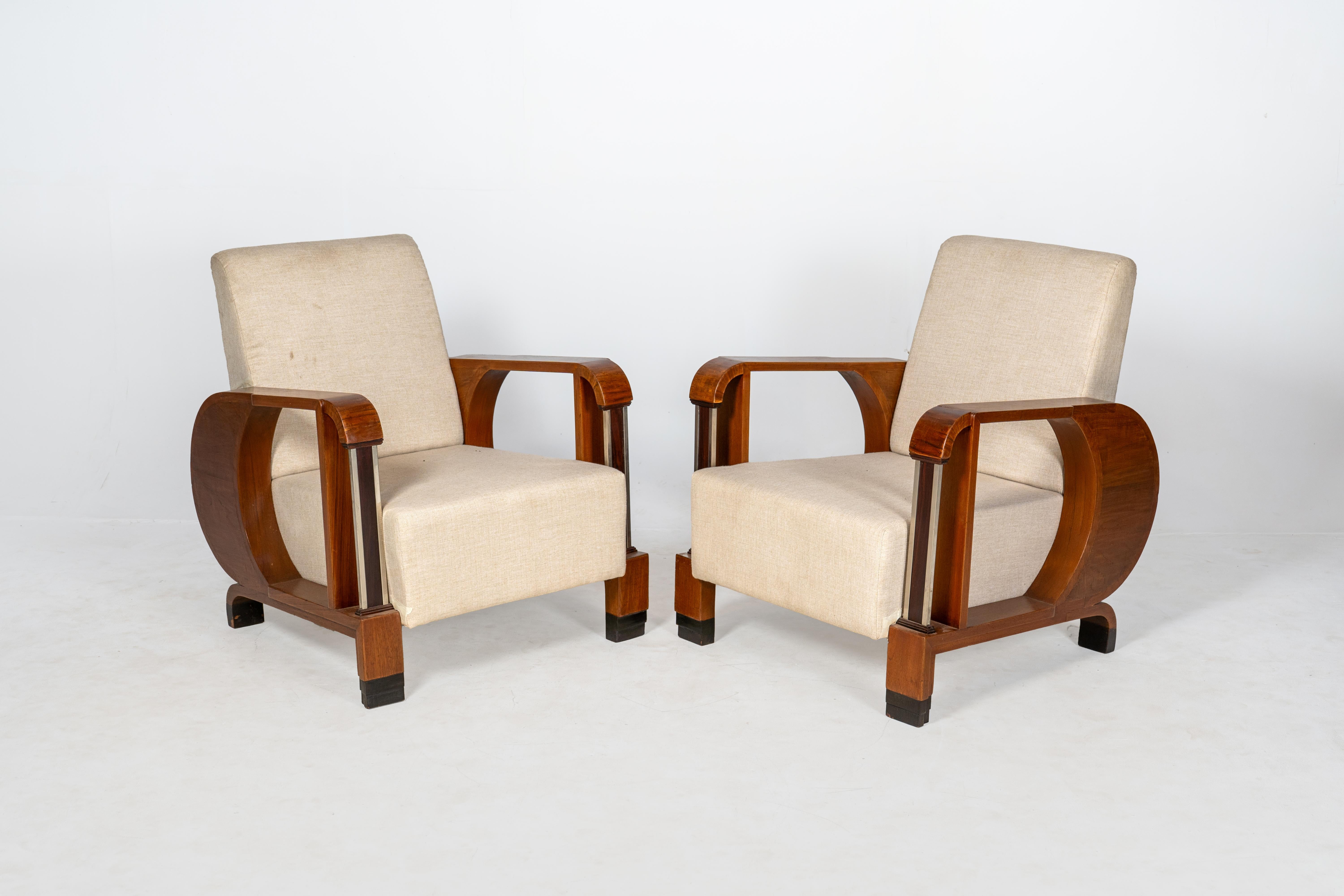 Ces fauteuils remarquables allient un style Art déco audacieux à un confort moderne. Fabriqué avec de riches cadres en bois de teck, le design présente des courbes et des lignes géométriques caractéristiques, accentuées par des supports cylindriques
