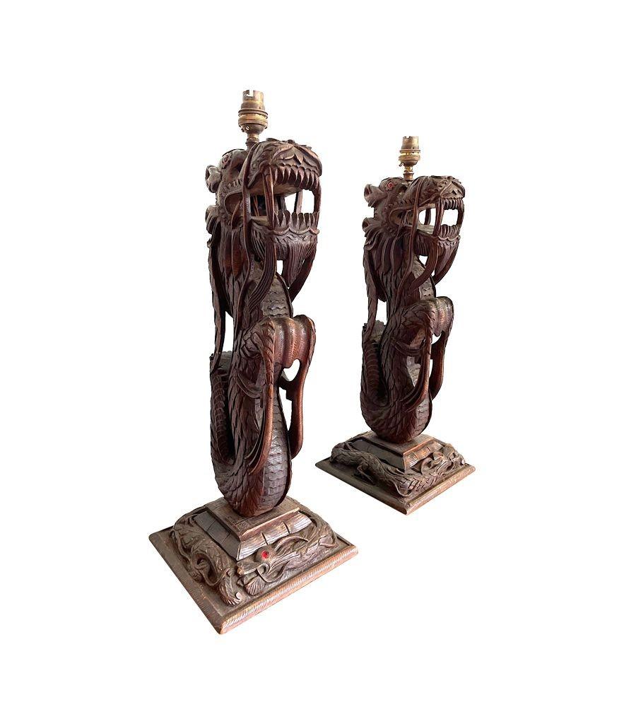 Paar kunstvoll geschnitzte burmesische Drachenlampen, jeweils auf geschnitztem Holz montiert (Frühes 20. Jahrhundert) im Angebot