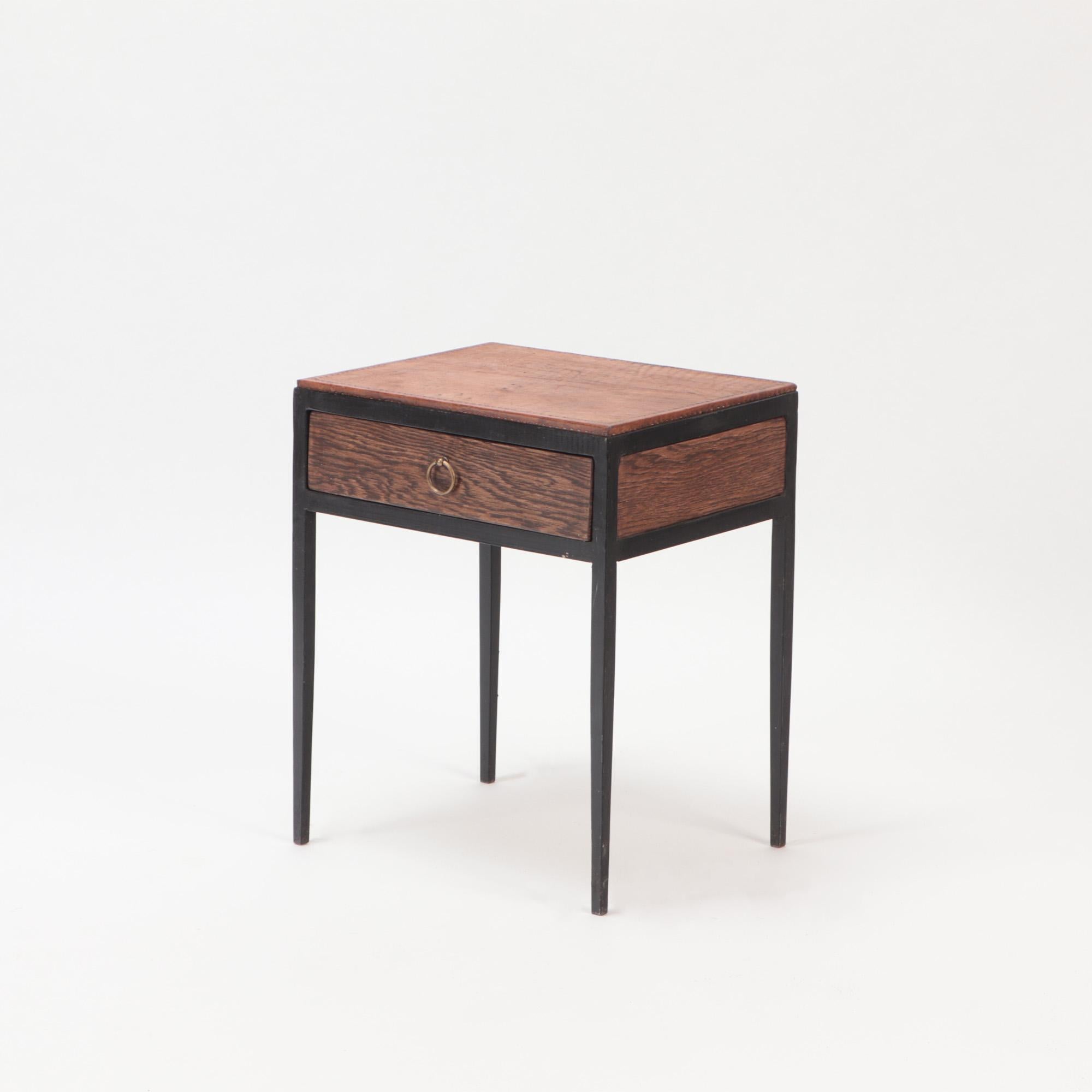 A pair of Iron and oak side tables or night stands with leather tops in the manner of Jean-Michel Frank. Contemporary.One drawer with brass ring handle.