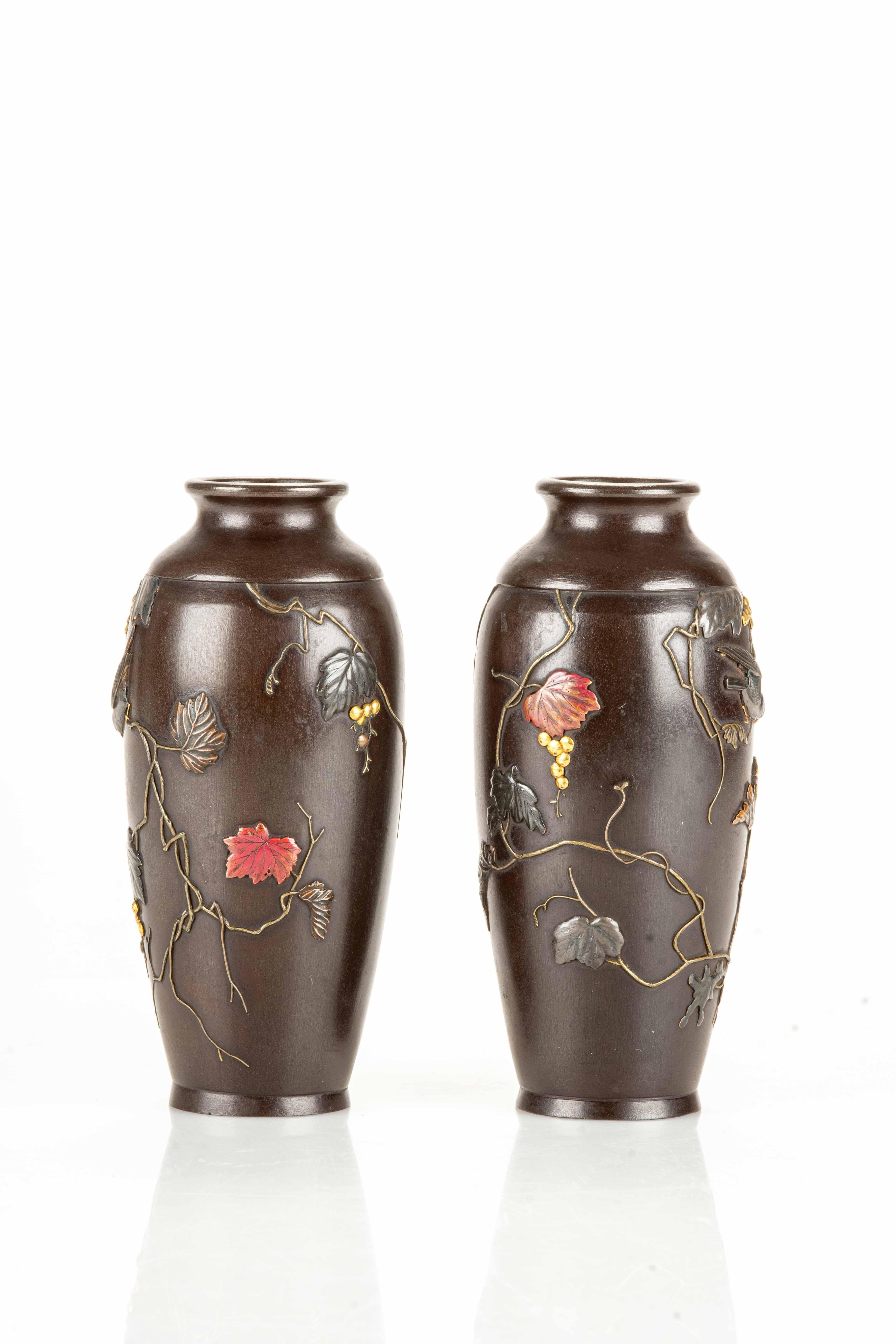 Una coppia di vasi in ferro, elegantemente lavorati e decorati con intarsi di rame e bronzo dorato. La decorazione raffigura una coppia di passeri in volo tra delicate foglie.

Periodo: Meiji, fine del XIX secolo.
Dimensioni: 13,5 x 6