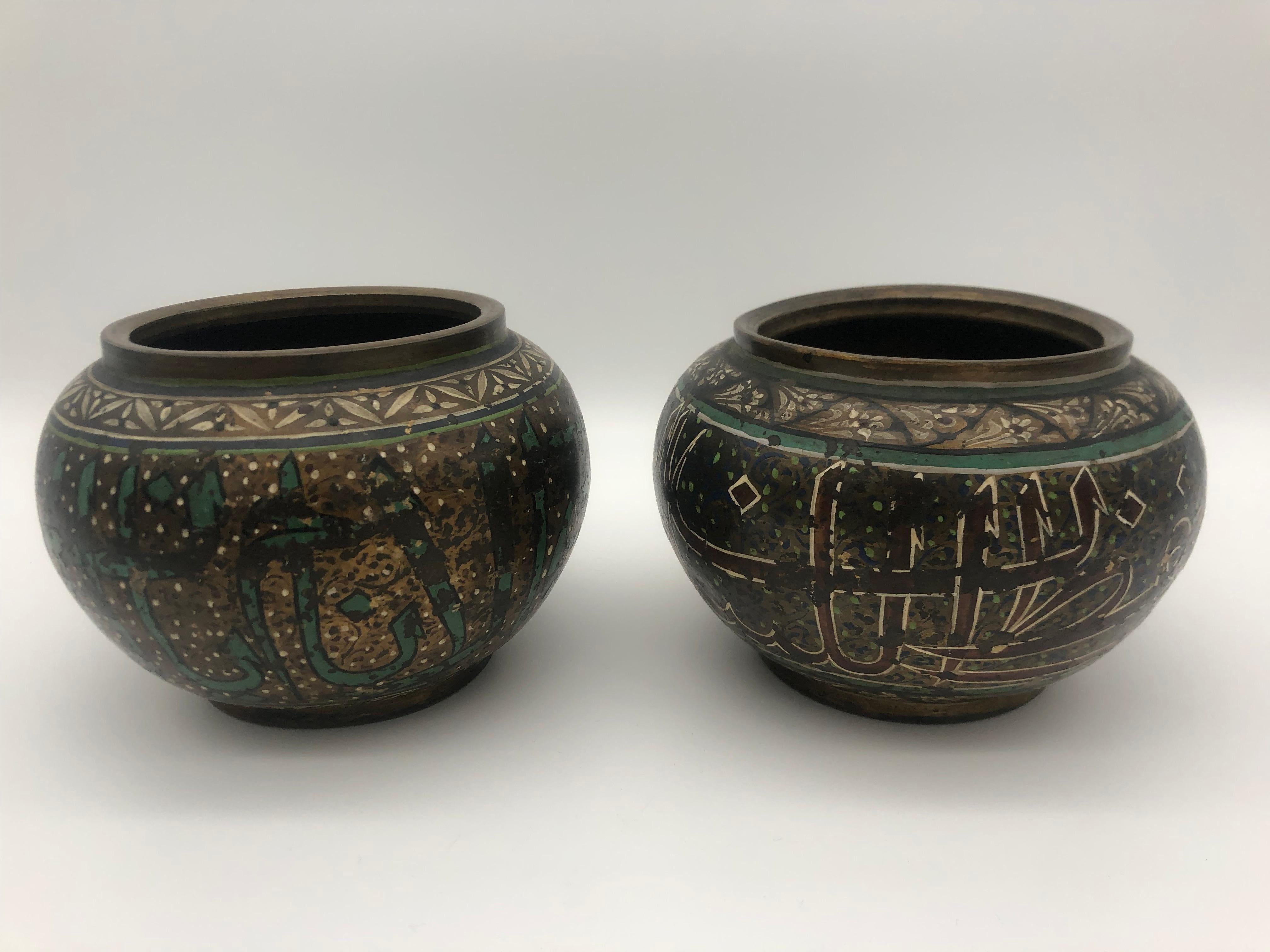 A find pair of Ottoman brass vases with enamel painted patterns and arab inscription on the surface.
Both with old ink written numbers on the bottom.

They are in good condition, although the paint on the surface is partly a bit rubbed, they don't