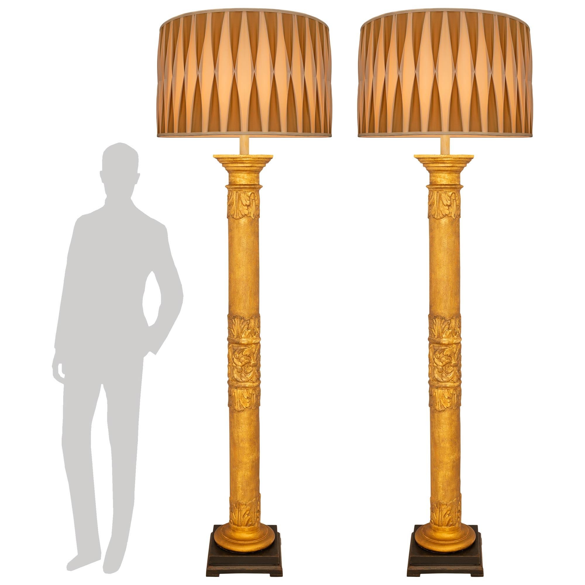 An impressive and very handsome pair of Italian 18th century Baroque st. Giltwood and patinated wood floor lamps. Each wonderful column that has been turned into a floor lamp is raised by a patinated forest green mottled edge square base and